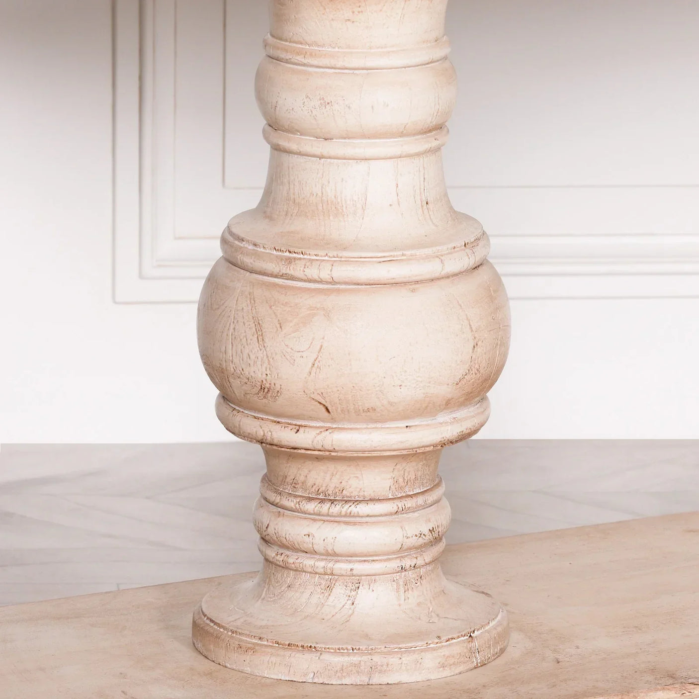 Close-up of rustic wooden dining table leg with turned design and light natural wood finish