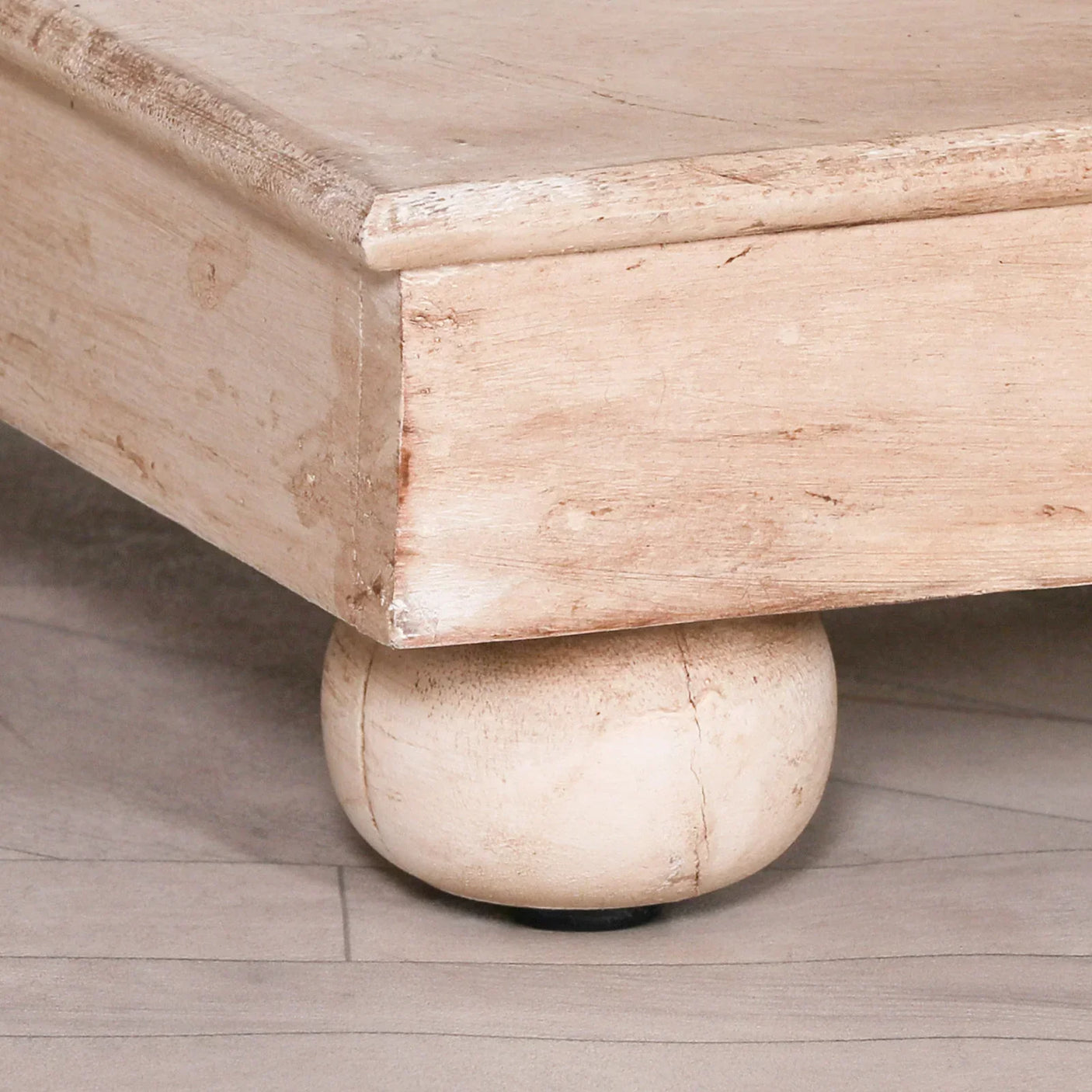 Light wood furniture corner with round bun foot on hard floor