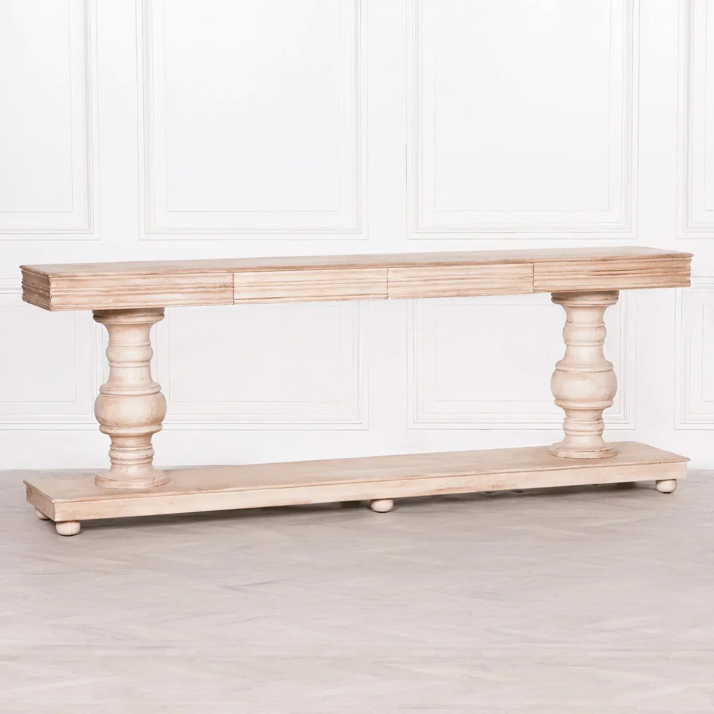 Light wood console table with turned legs and plinth base against white panelled wall