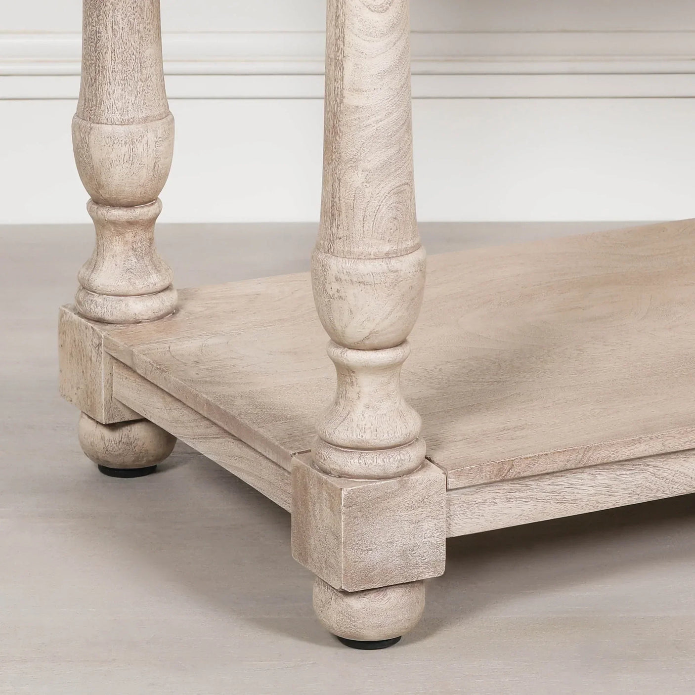 Close-up of wooden coffee table leg and lower shelf in light finish
