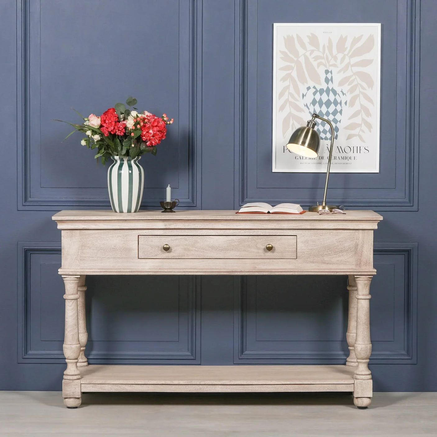 Rustic console table with drawer and shelf, styled with vase, lamp, and open book