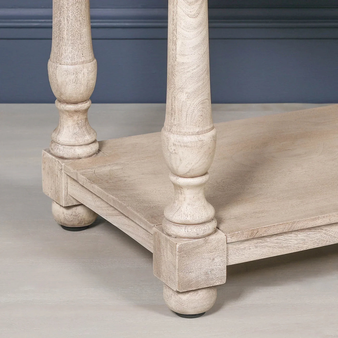 Light wood coffee table corner with turned legs and lower shelf detail
