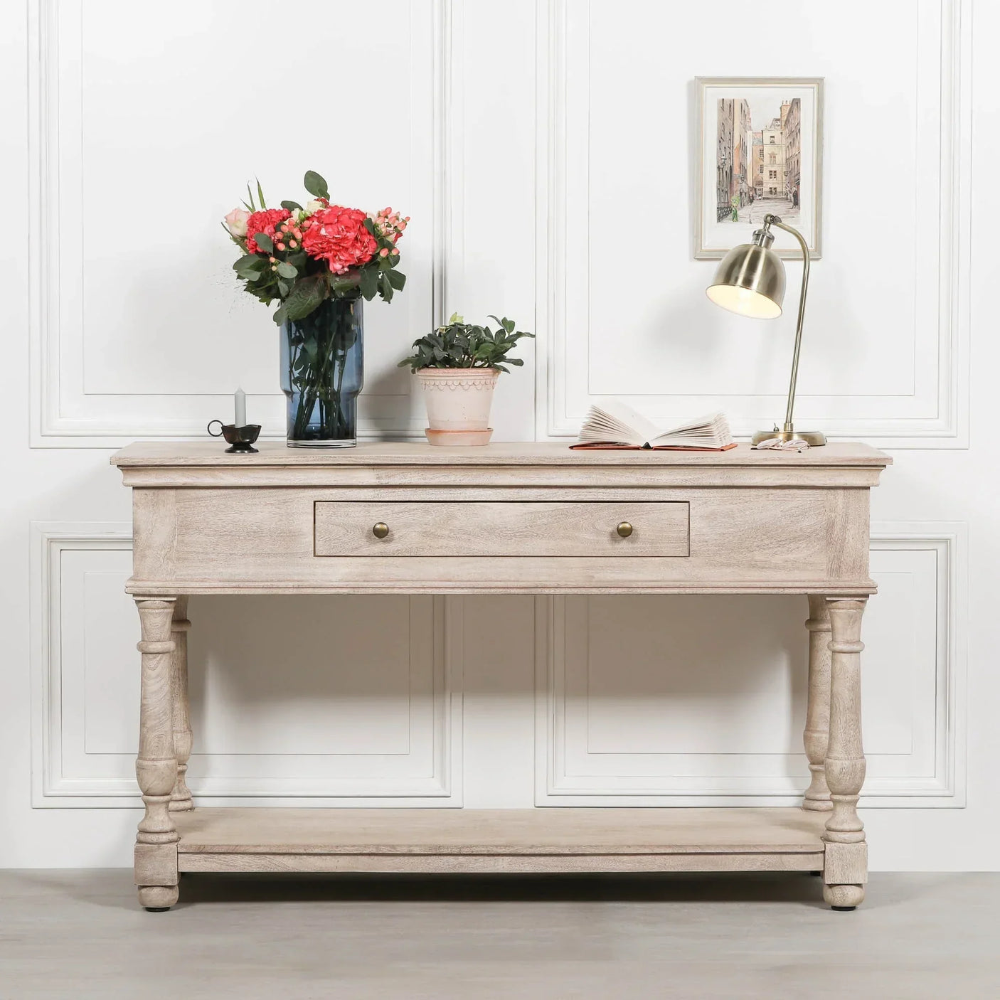 Light wood console table with drawer, decorated with vase, lamp, books and potted plant