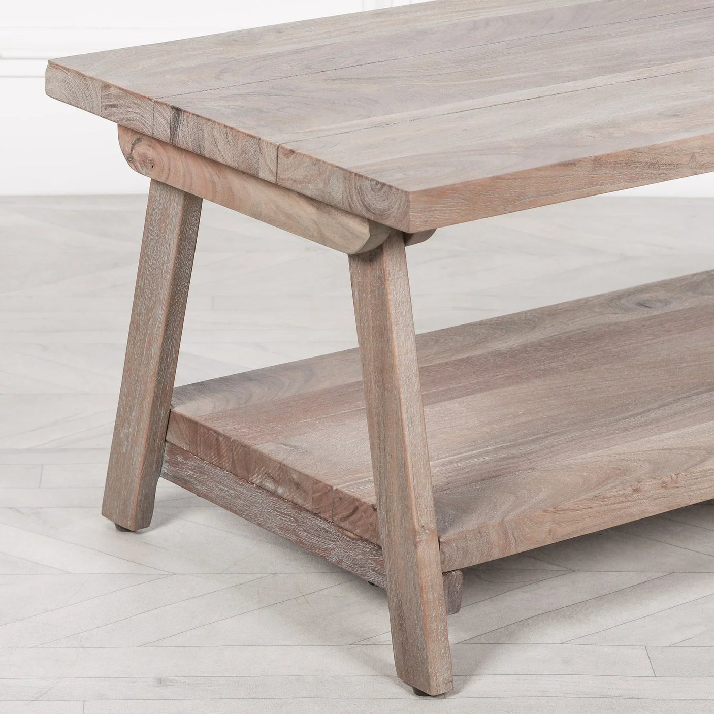 Solid wood coffee table with angled legs and lower shelf on light parquet floor