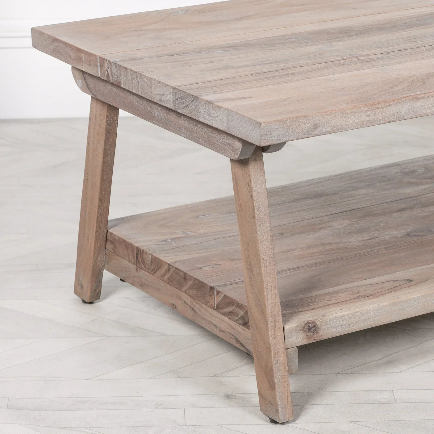 Light wood coffee table with angled legs and lower storage shelf on herringbone floor