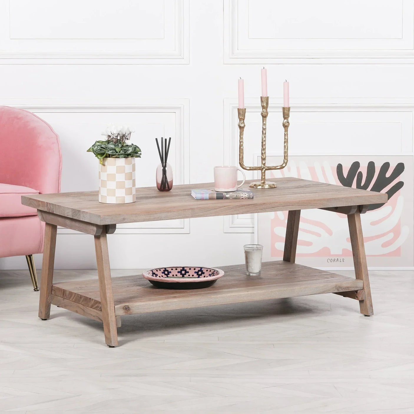 Light wood coffee table with lower shelf, styled with candles, plant, and decorative items