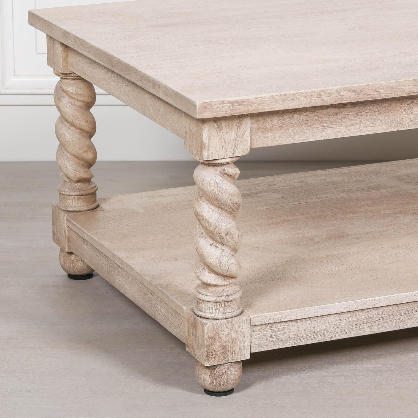 Light wood coffee table with lower shelf and twisted carved legs on wooden floor