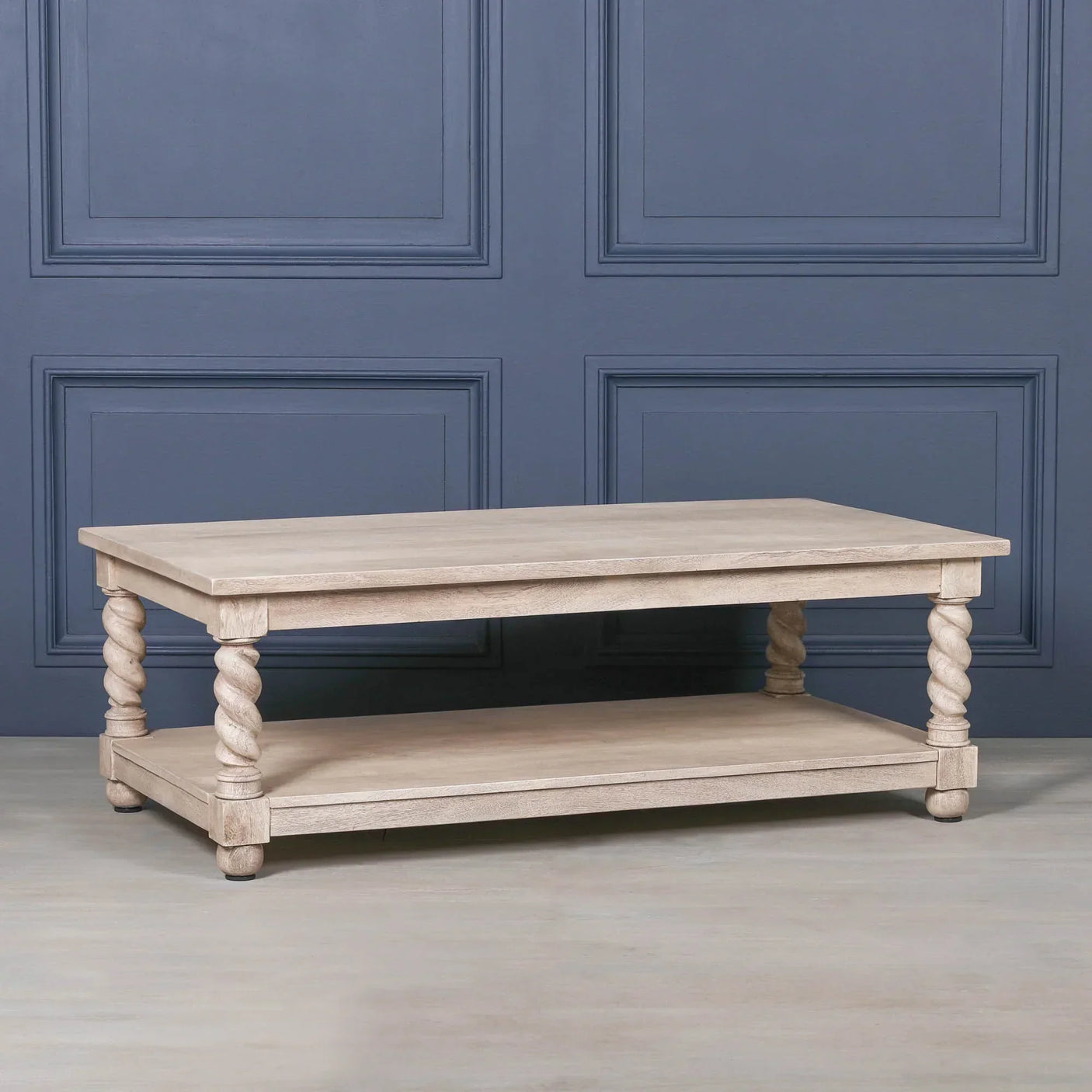Oak coffee table with lower shelf and twisted wooden legs against blue wall