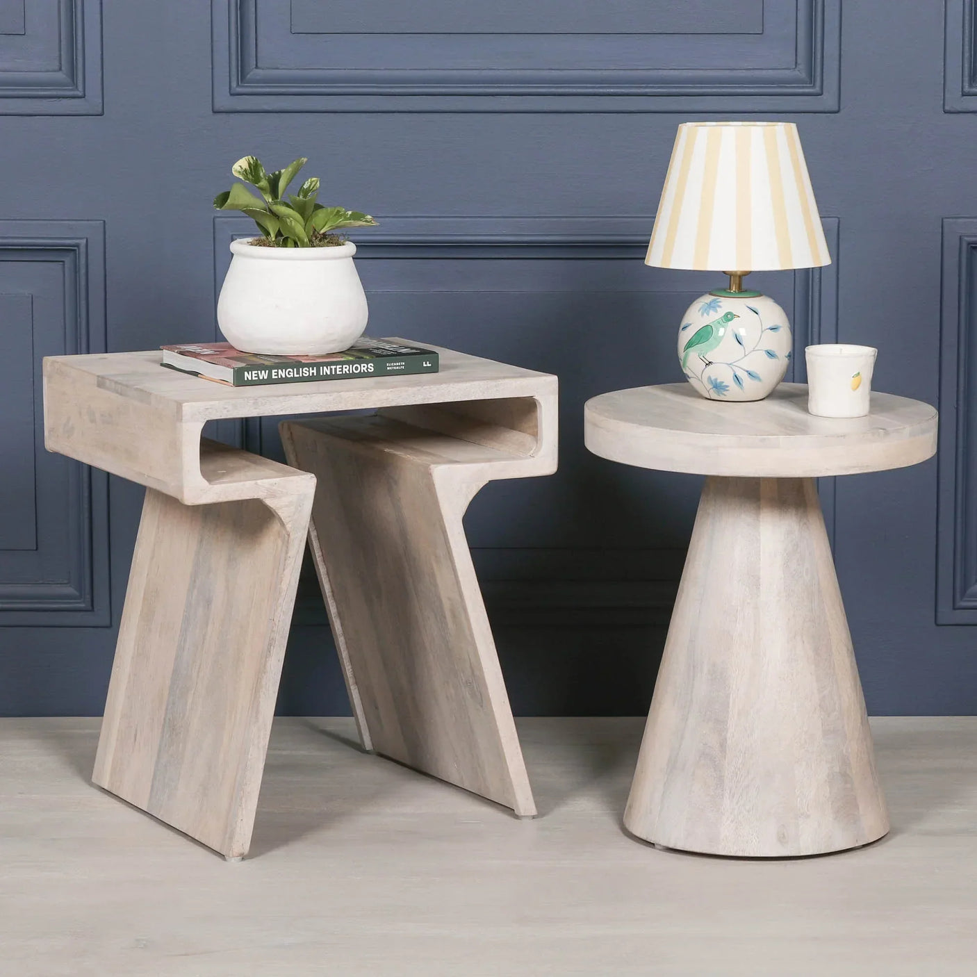 Set of two modern wood side tables with whitewashed finish styled in front of blue wall