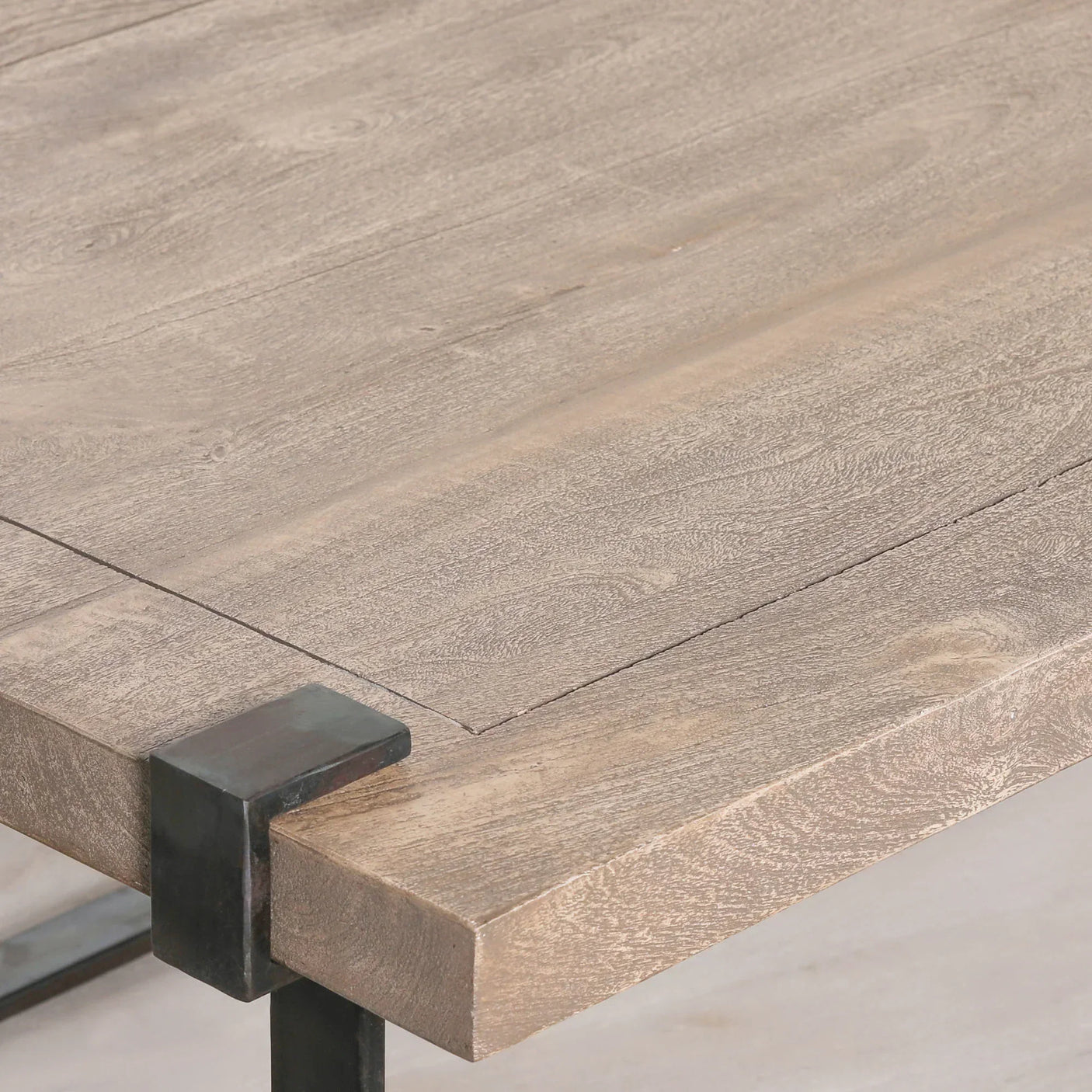 Light wood dining table top with black metal corner leg and visible wood grain