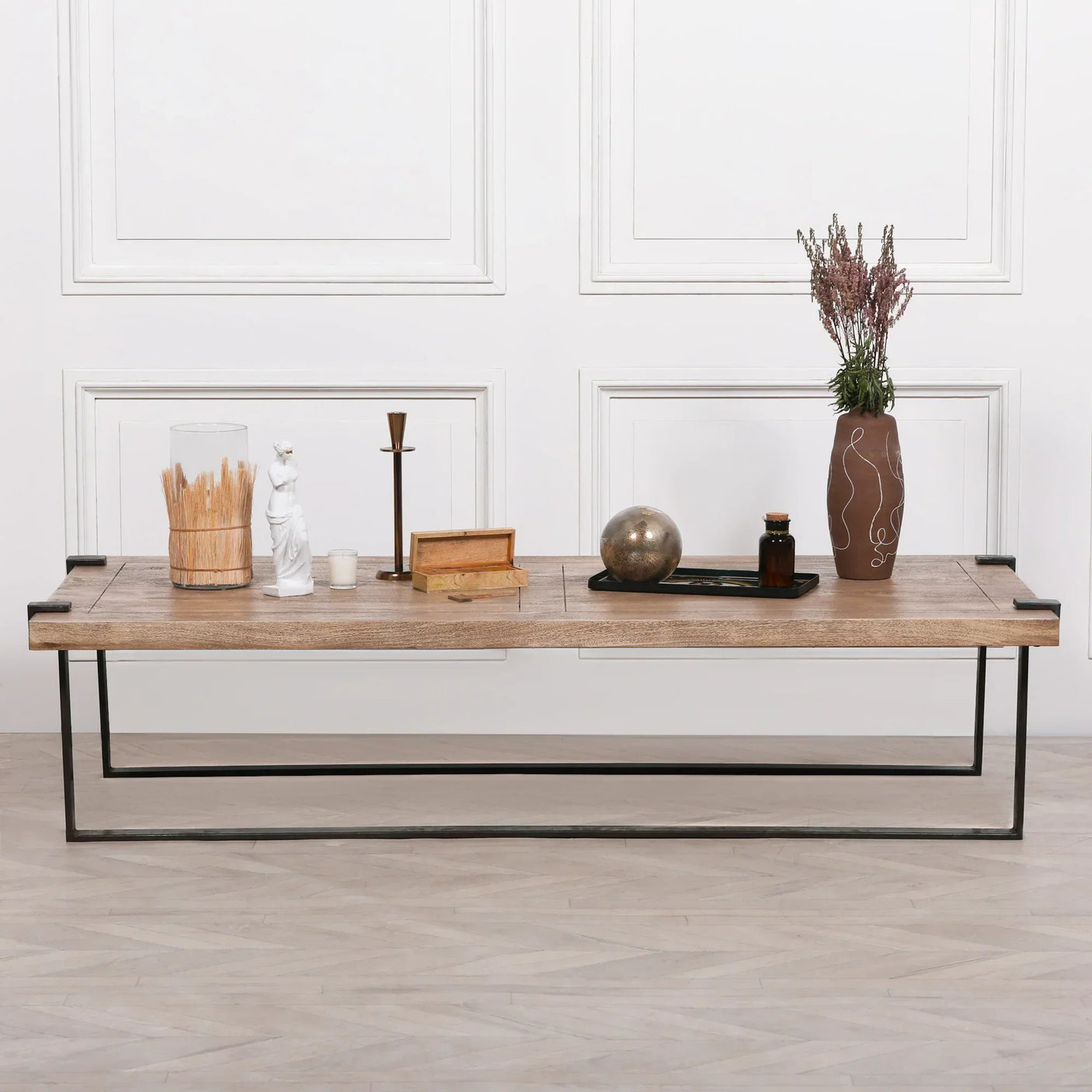 Rectangular wooden coffee table with metal frame styled with vases, tray, and decorative items