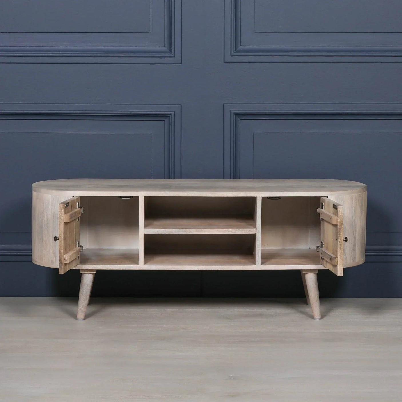Light wood TV unit with open shelves and side cabinets, angled legs, against blue wall