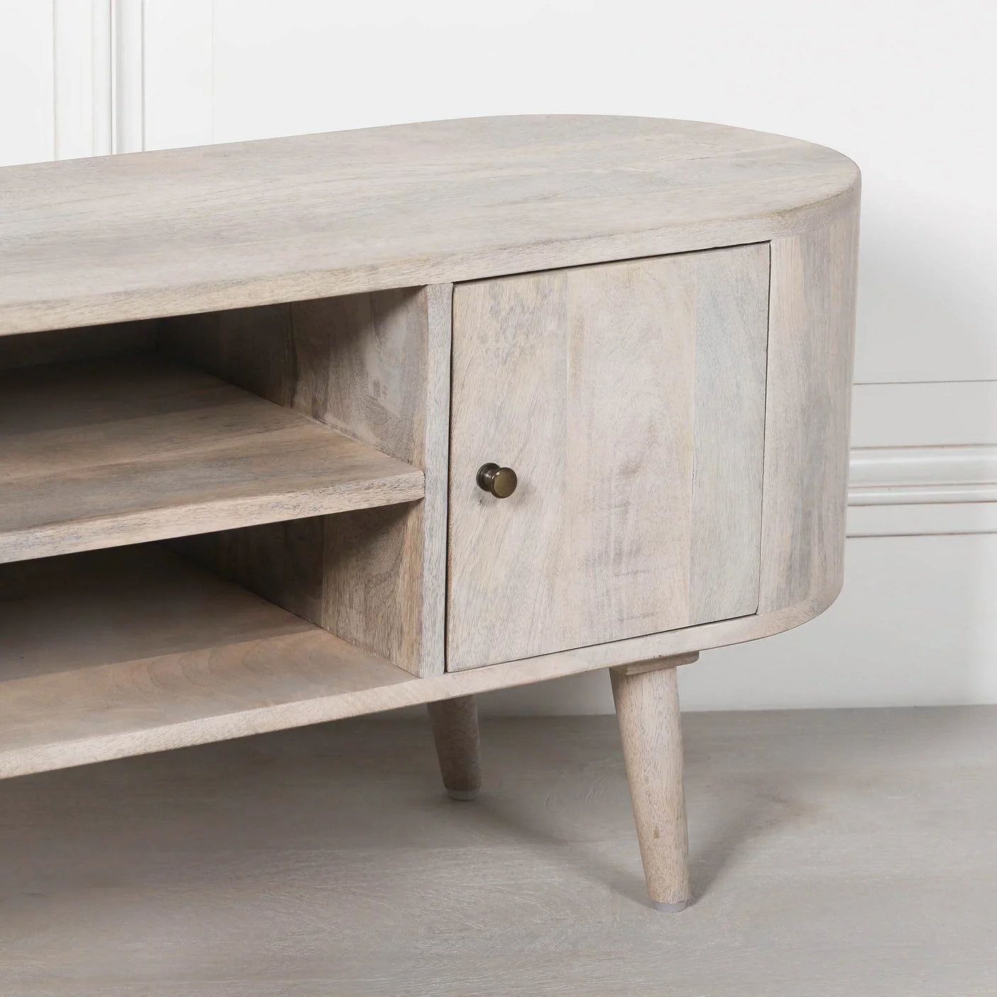 Light wood TV unit with open shelves and single door cabinet on angled legs