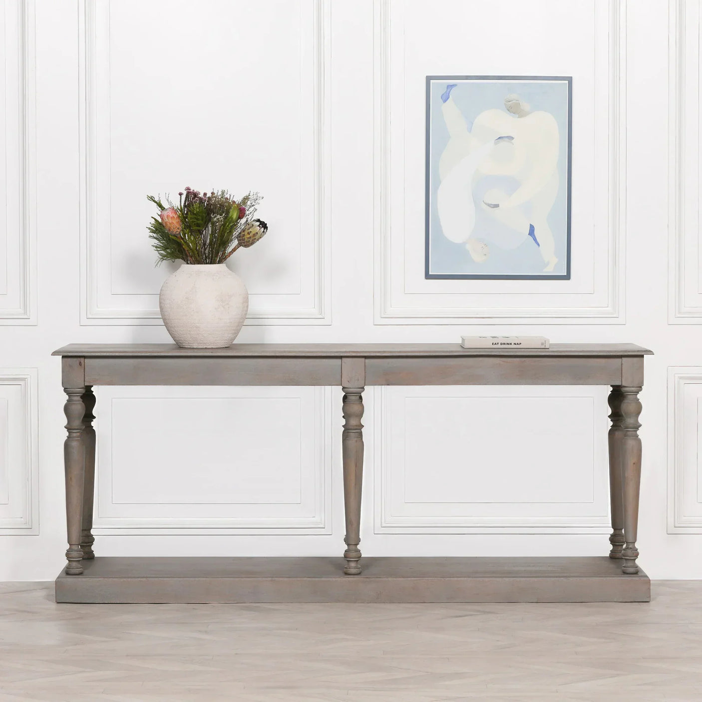Grey wooden console table with turned legs, vase of flowers and book in modern hallway setting