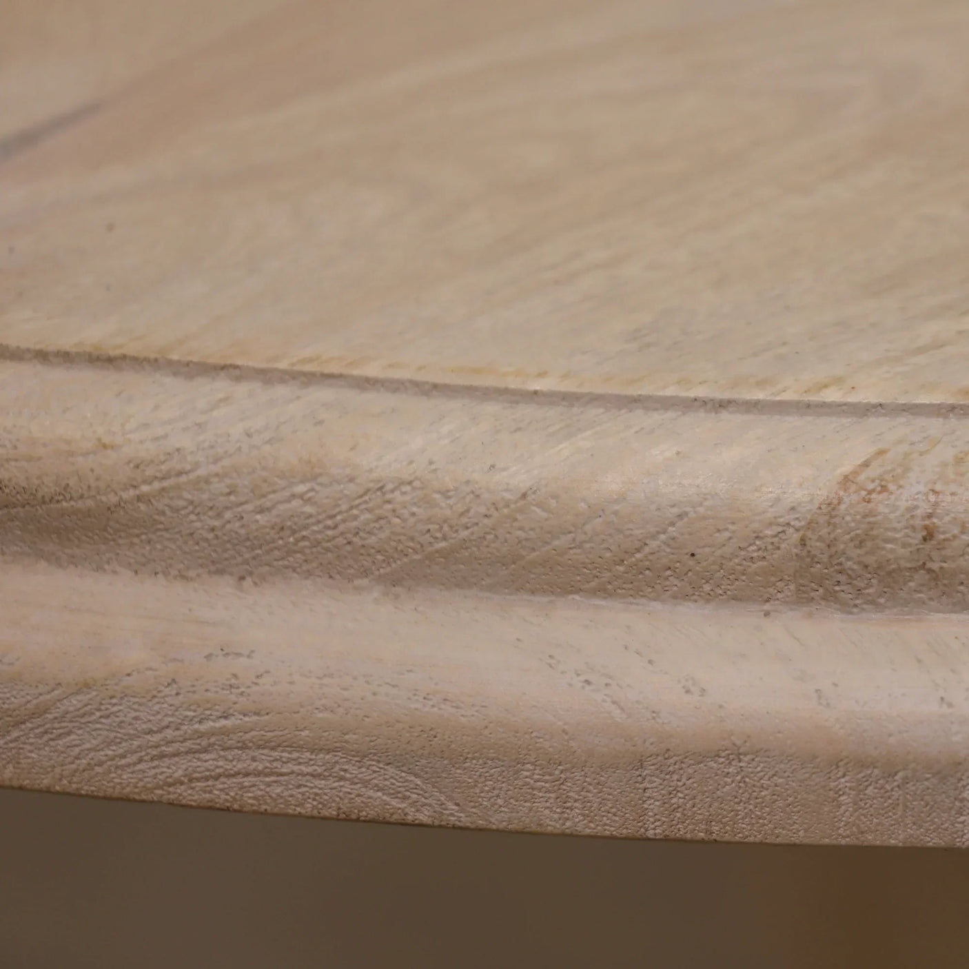 Closeup of round mango wood dining table edge with natural wood grain texture