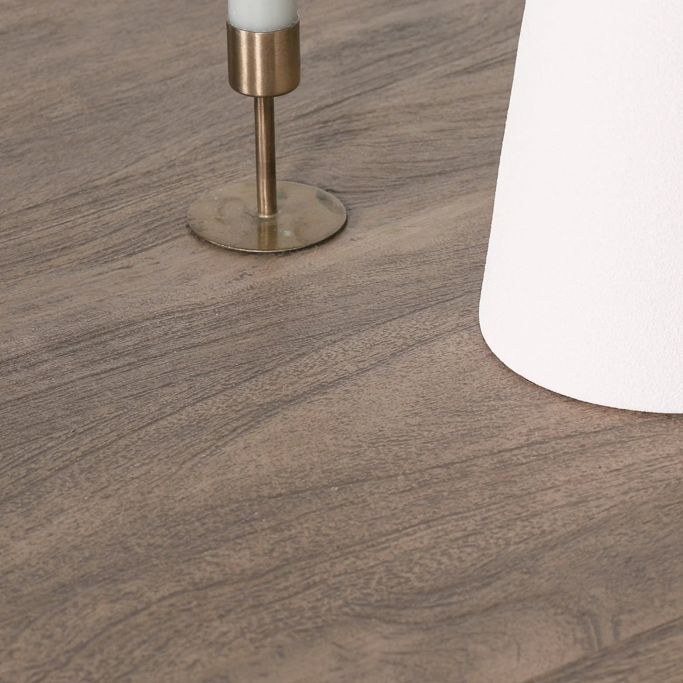 Close-up of wood coffee table surface with brass candle holder and white vase