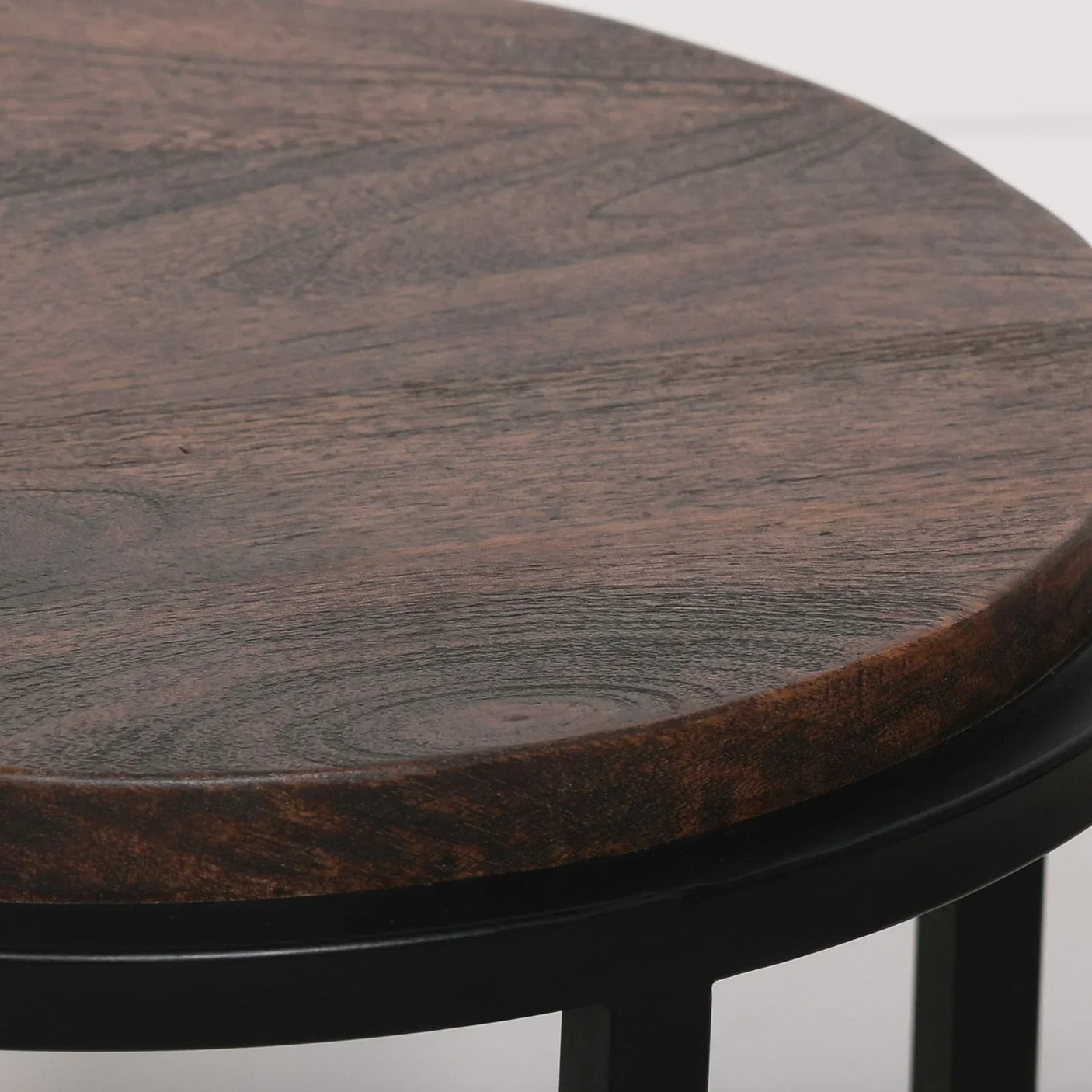 Round wooden coffee table top with visible grain and black metal legs close view