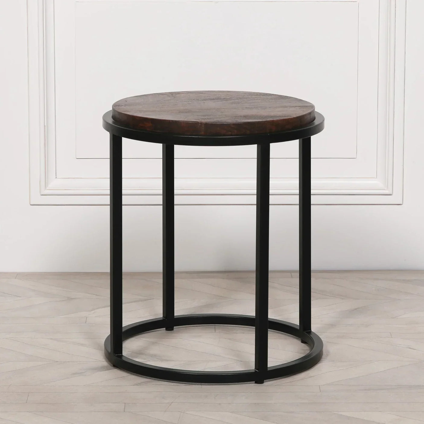 Round wooden side table with dark top and black metal frame on light wood floor