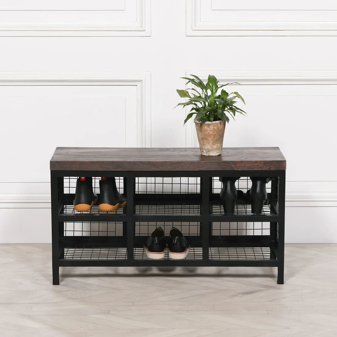 Black metal and wood shoe bench with grid shelves and plant on top, entryway storage unit