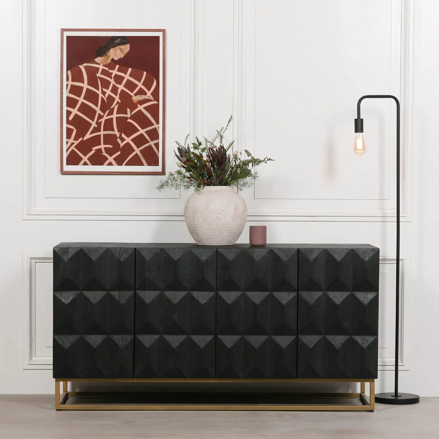 Black geometric sideboard with gold base, ceramic vase, and modern floor lamp in living room