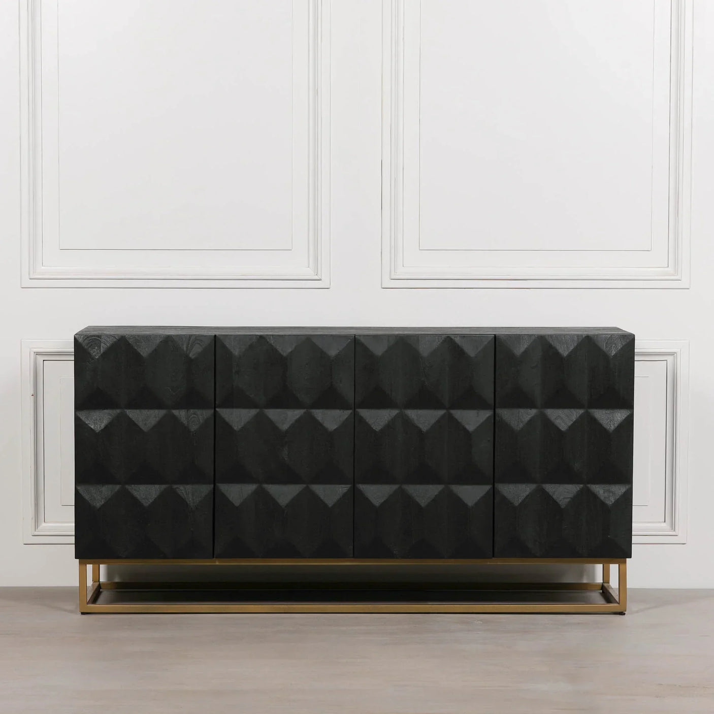 Black geometric sideboard with textured front panels on gold metal base against white wall