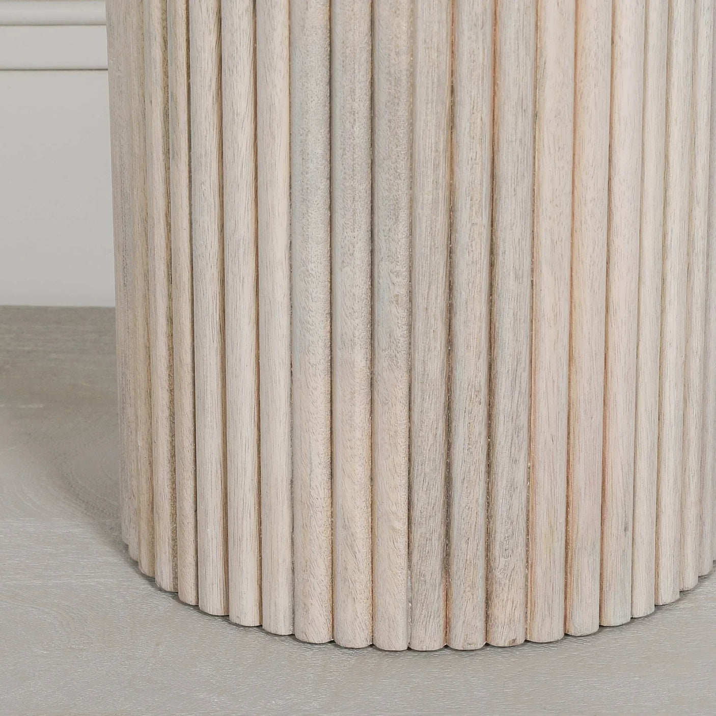 Light wood side table with vertical fluted panel detail, close-up of cylindrical base