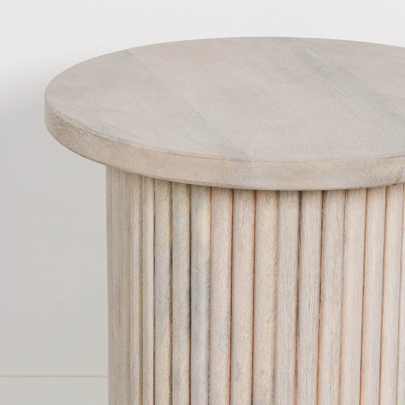 Round wooden side table with ribbed cylindrical base and light natural finish