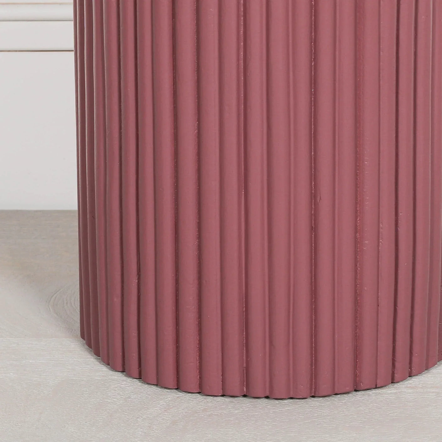 Closeup of ribbed pink side table base on light wood floor