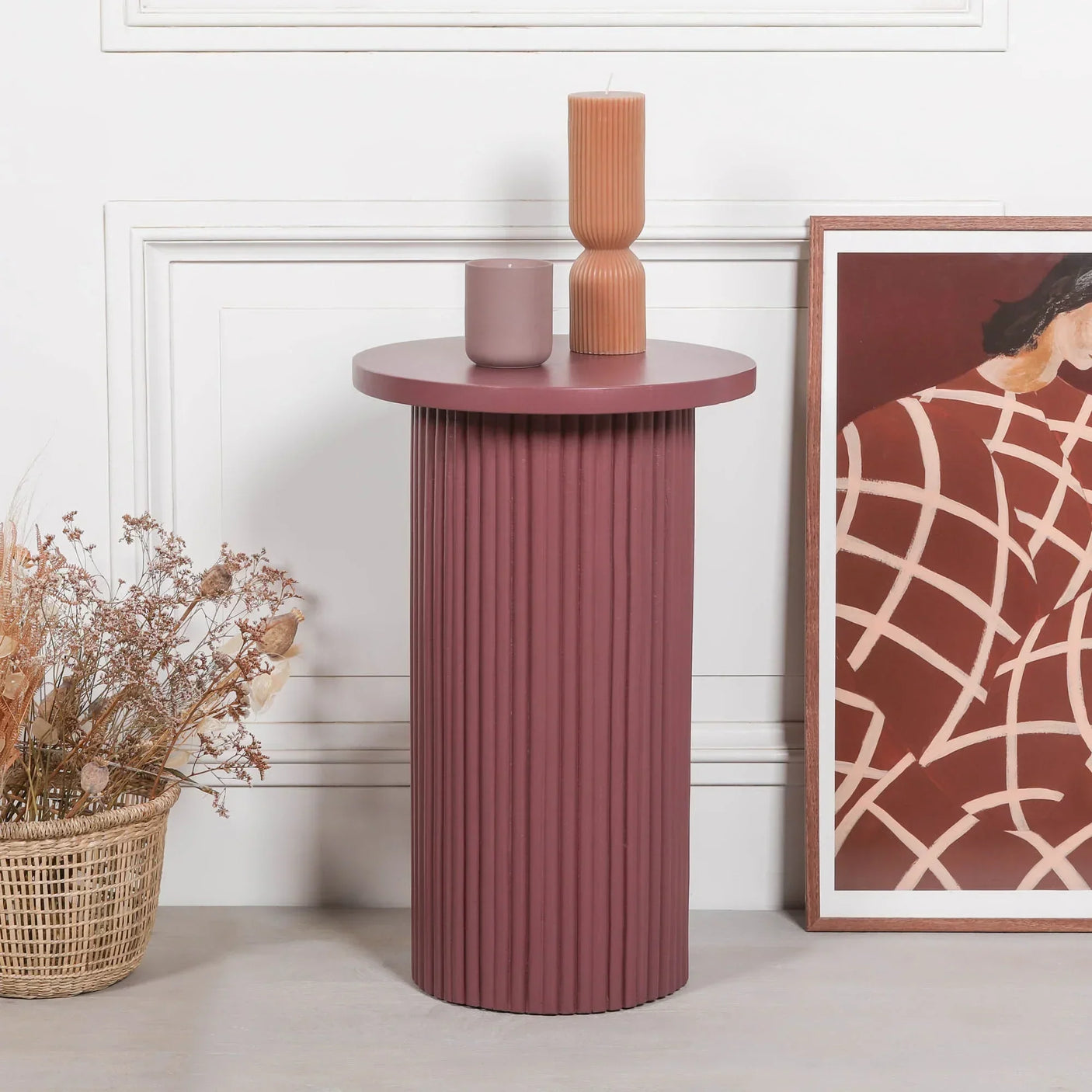 Round mauve accent side table with ribbed base, styled with candles and a framed wall art