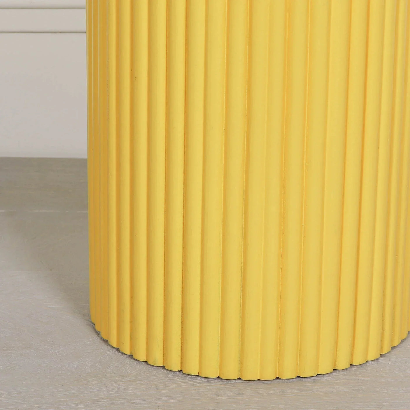 Yellow ribbed side table with vertical grooves on light floor