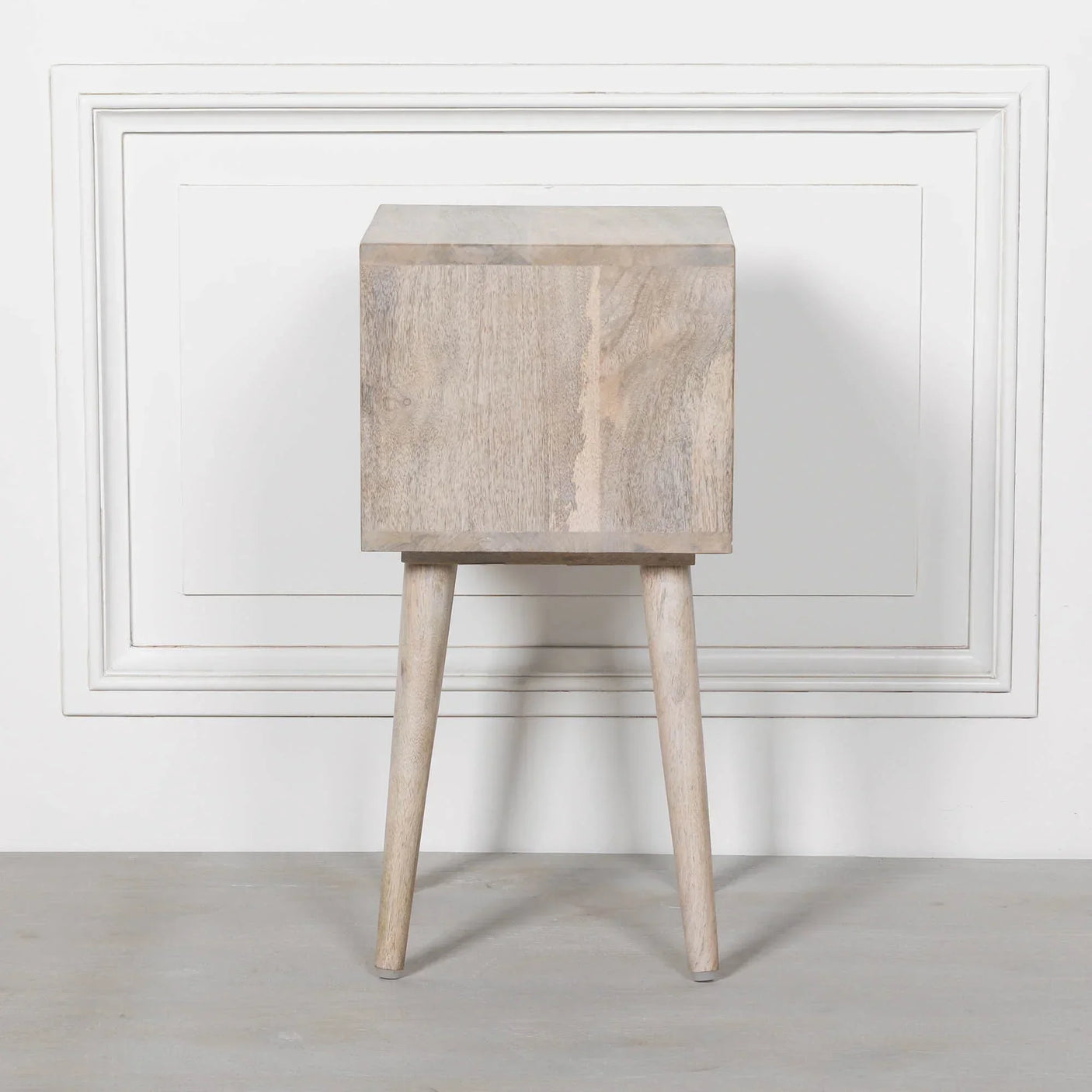 Solid wood bedside table with two legs in a light natural finish against white wall