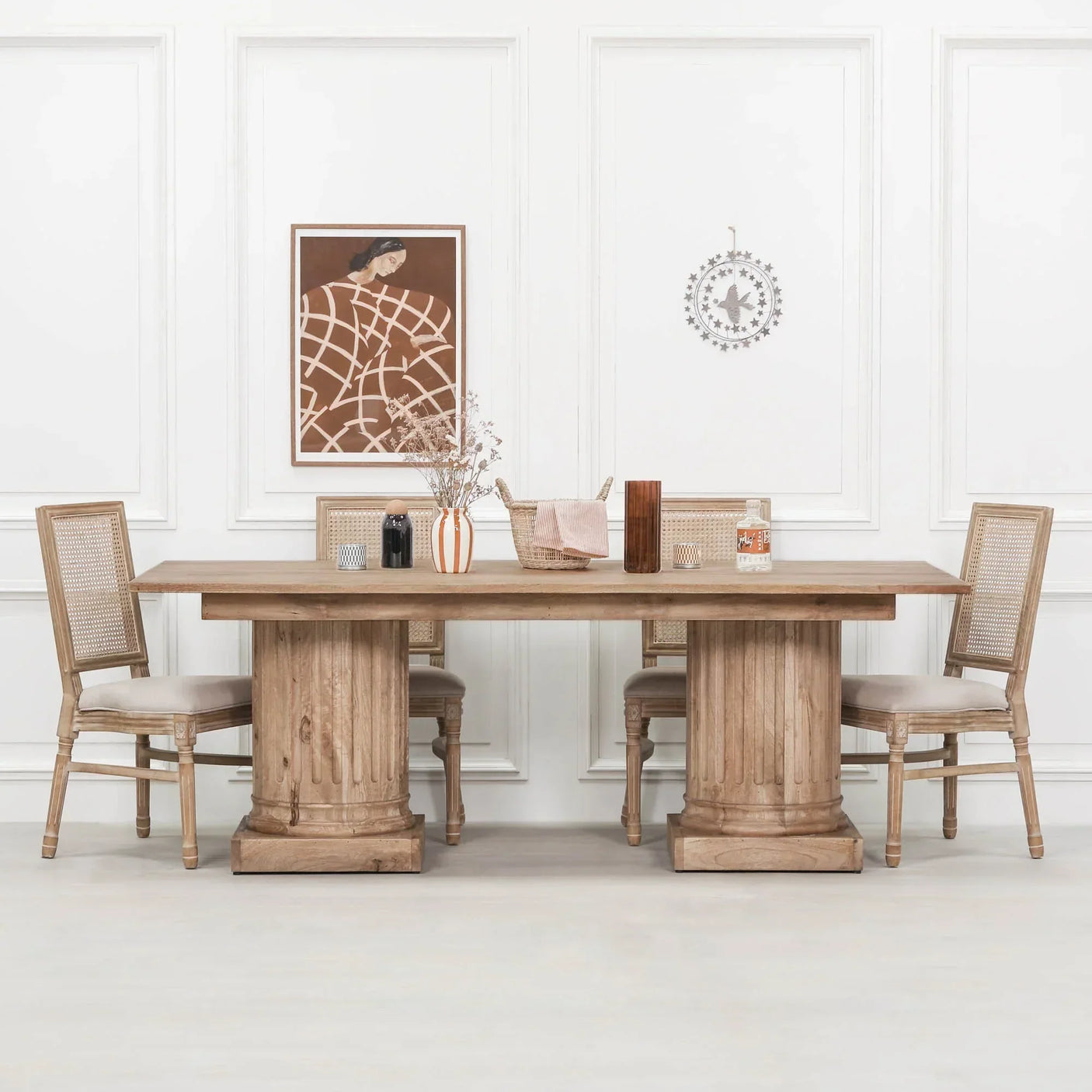 Rectangular oak dining table with carved pedestal base and four rattan-back chairs in white room