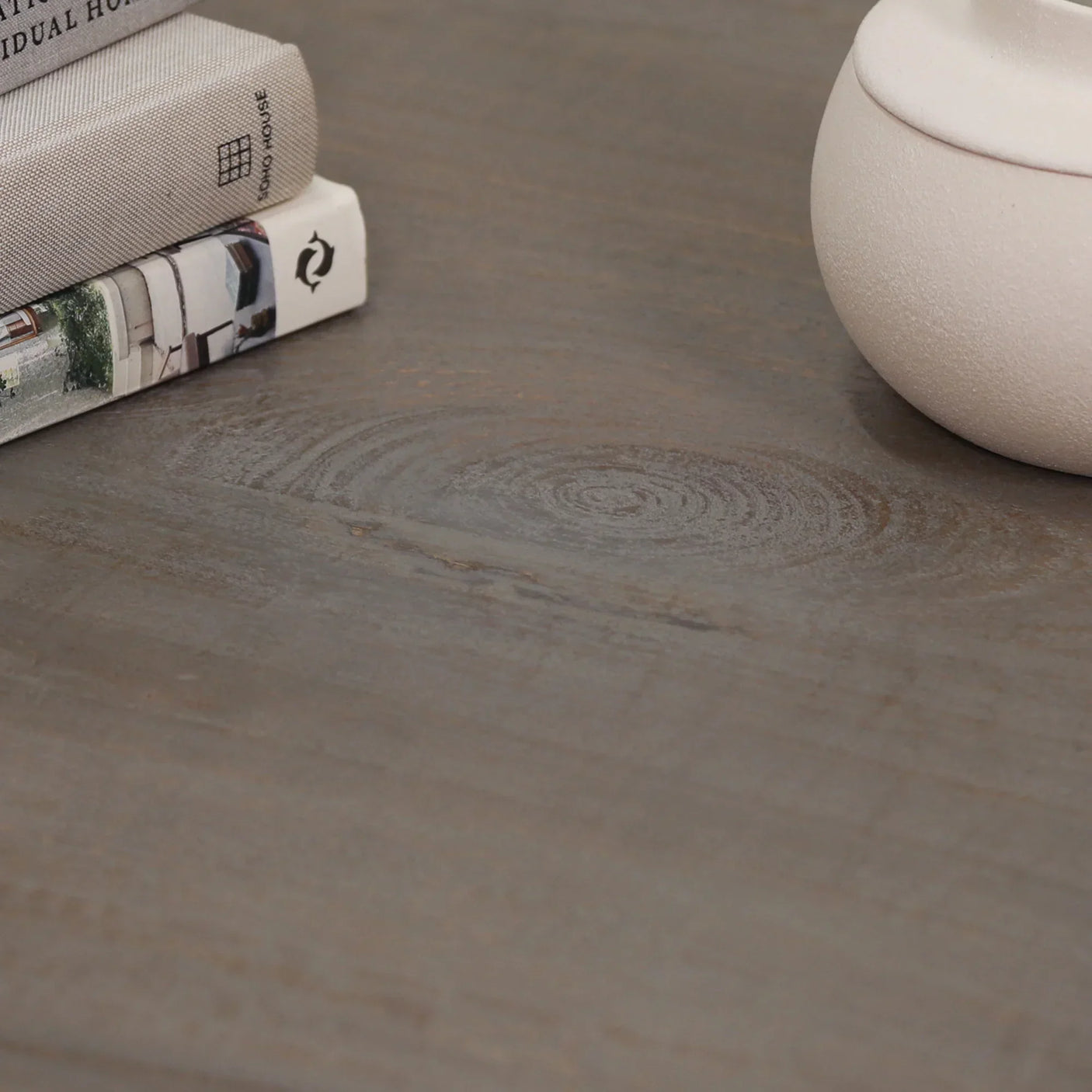 Closeup of wooden table surface with textured grain, books and ceramic pot on top