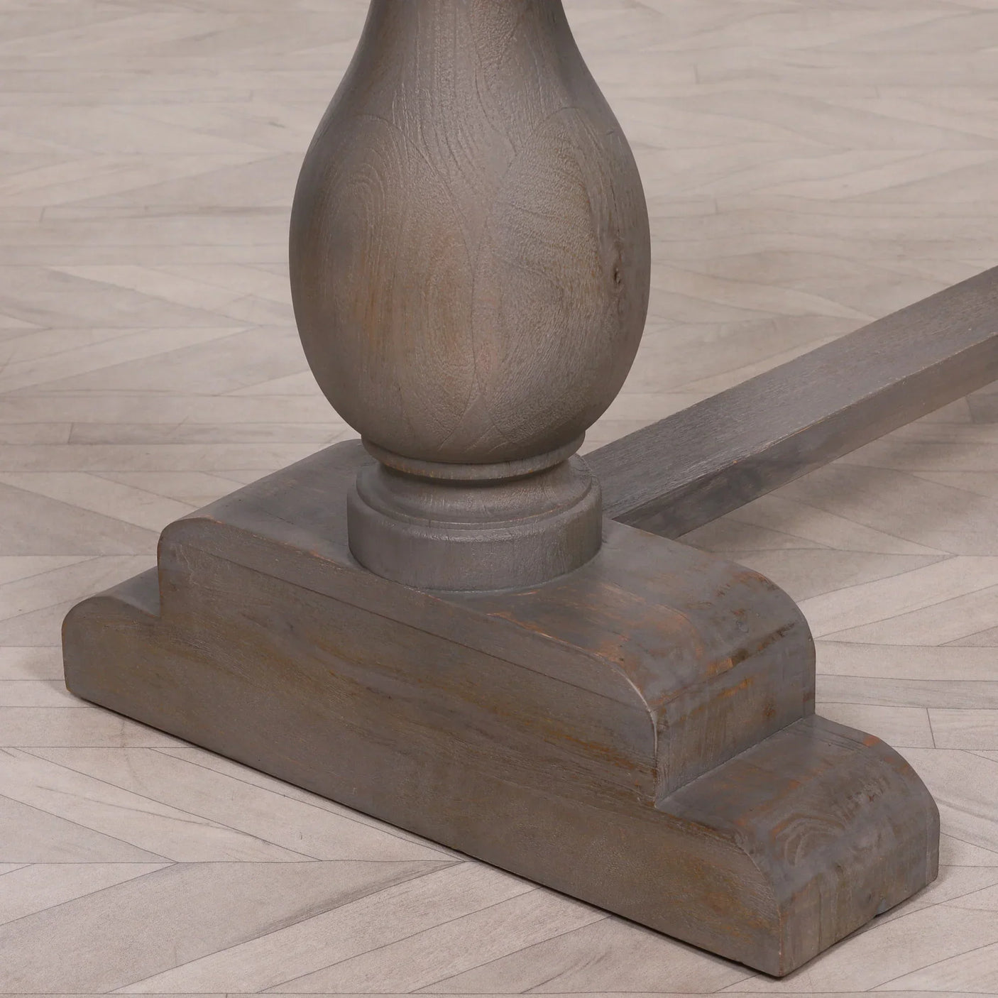 Rustic wooden dining table base with carved pedestal on parquet flooring