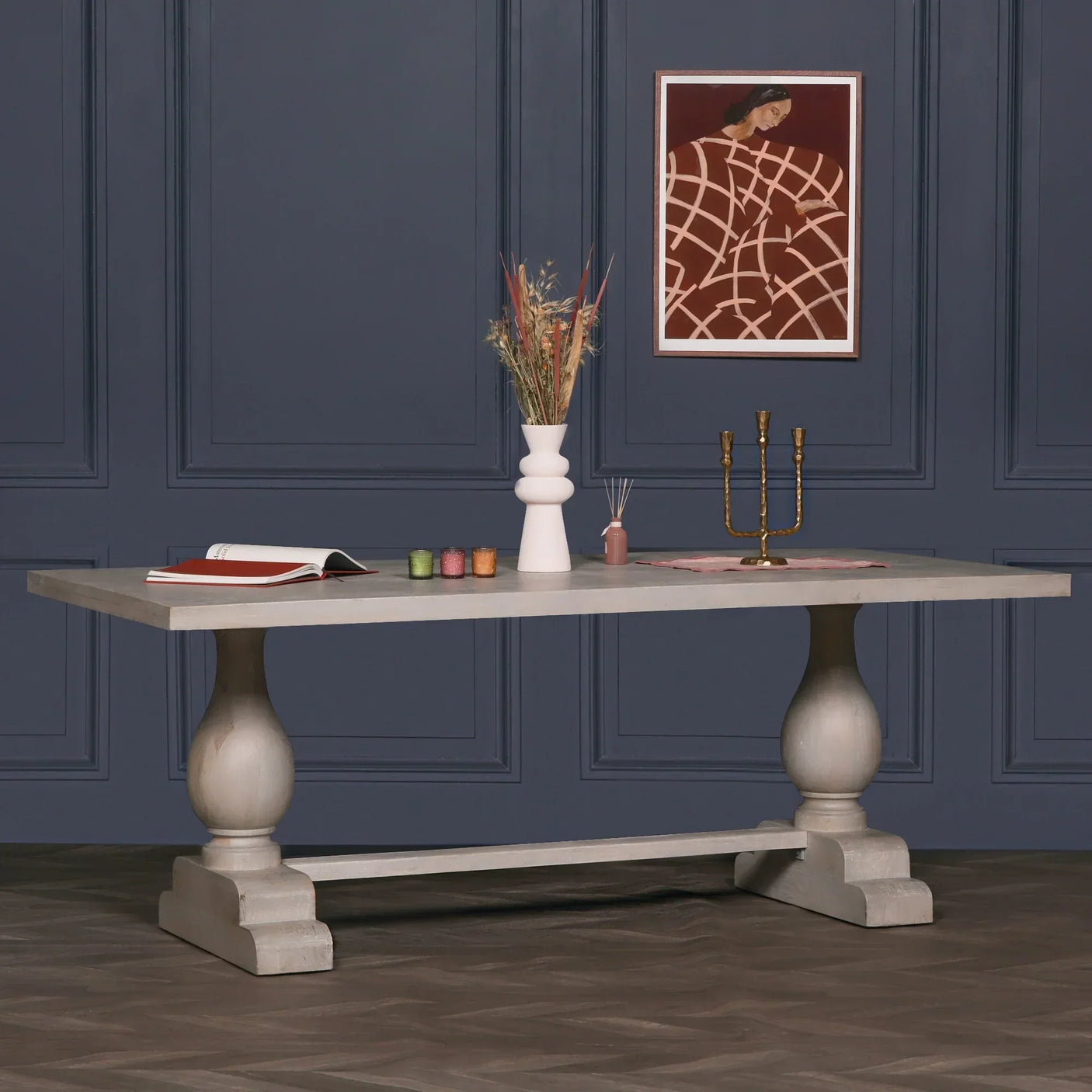 Rectangular grey wooden dining table with turned legs styled against a navy panelled wall