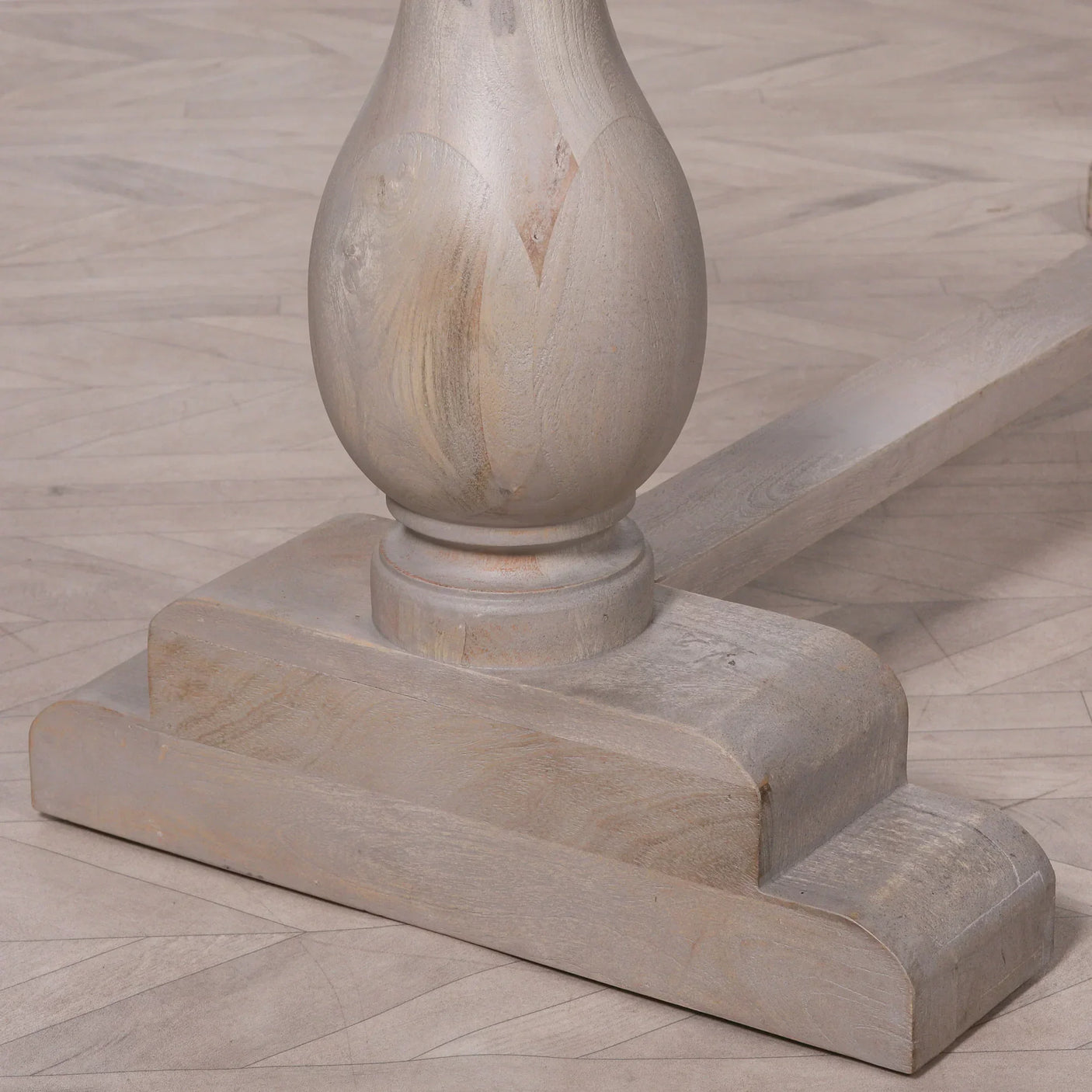 Rustic wood dining table base with curved pedestal and distressed finish on parquet floor