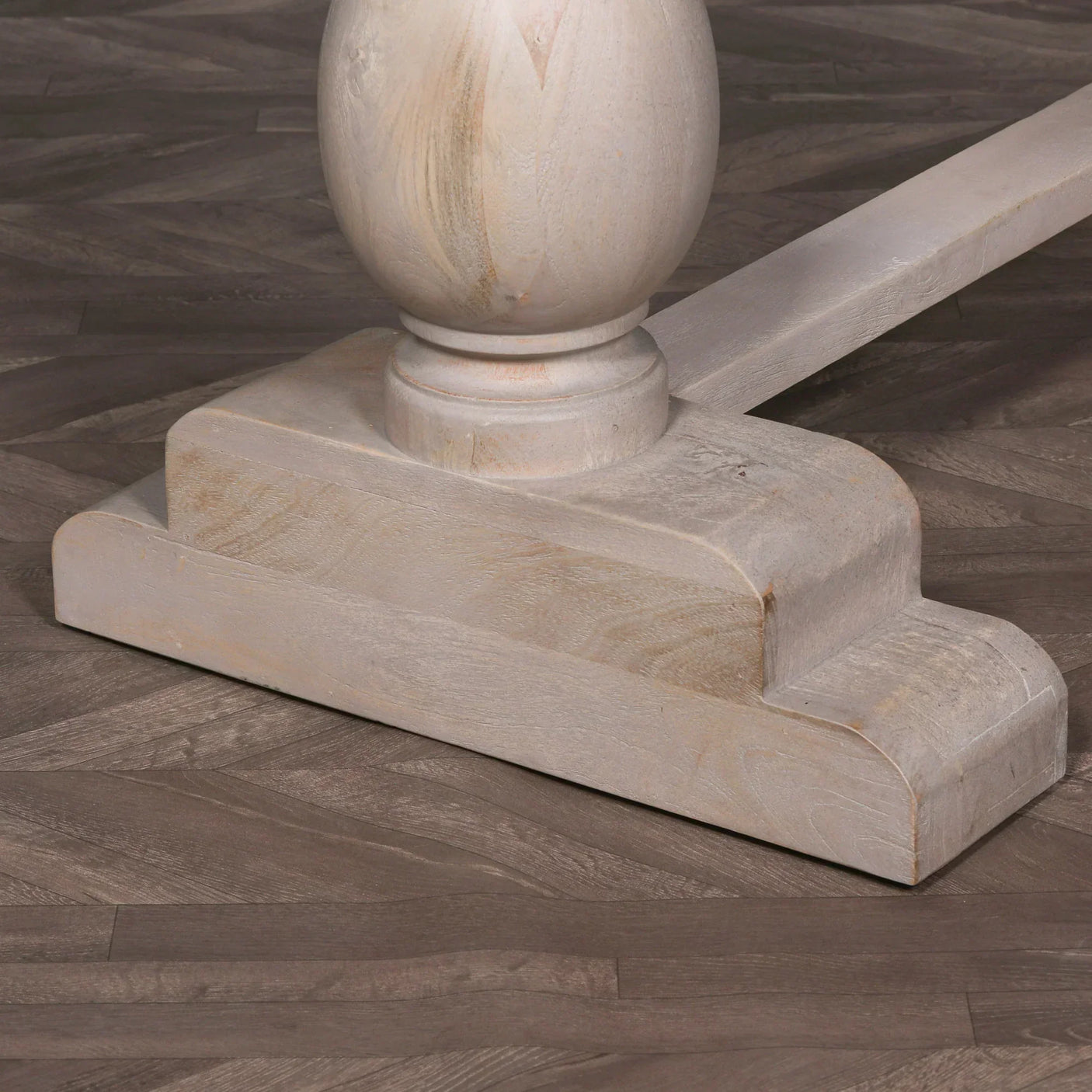 Light wood dining table pedestal base with curved edge detail on herringbone floor