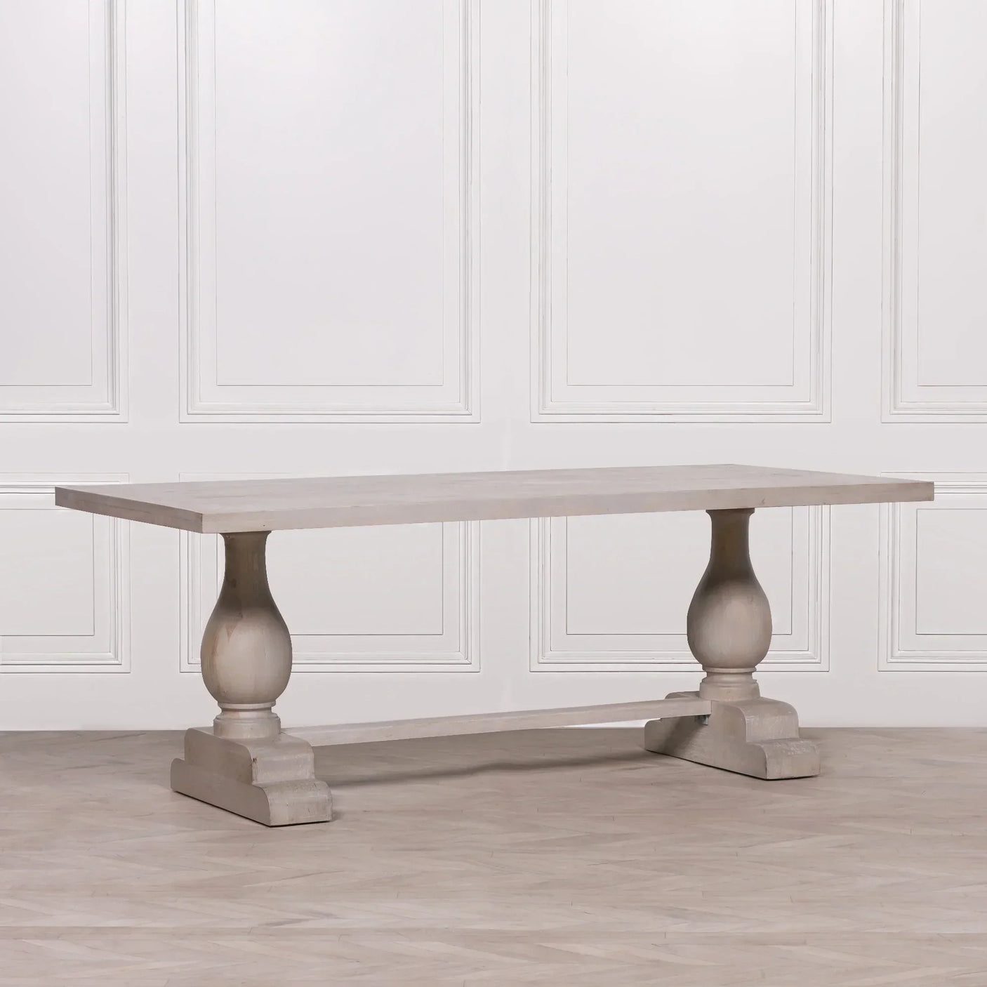 Rectangular wooden dining table with pedestal base in light oak finish against panel wall