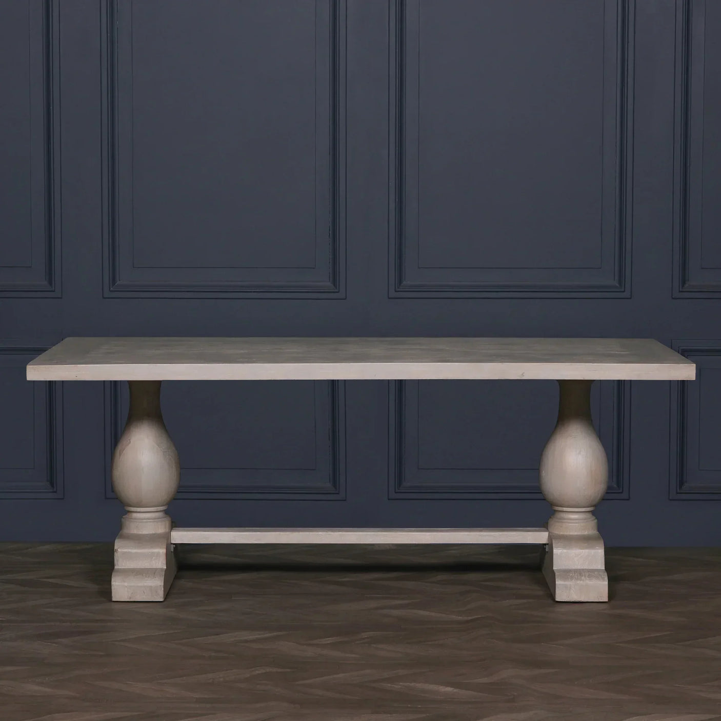 Solid wood dining table with rectangular top and turned double pedestal legs on herringbone floor