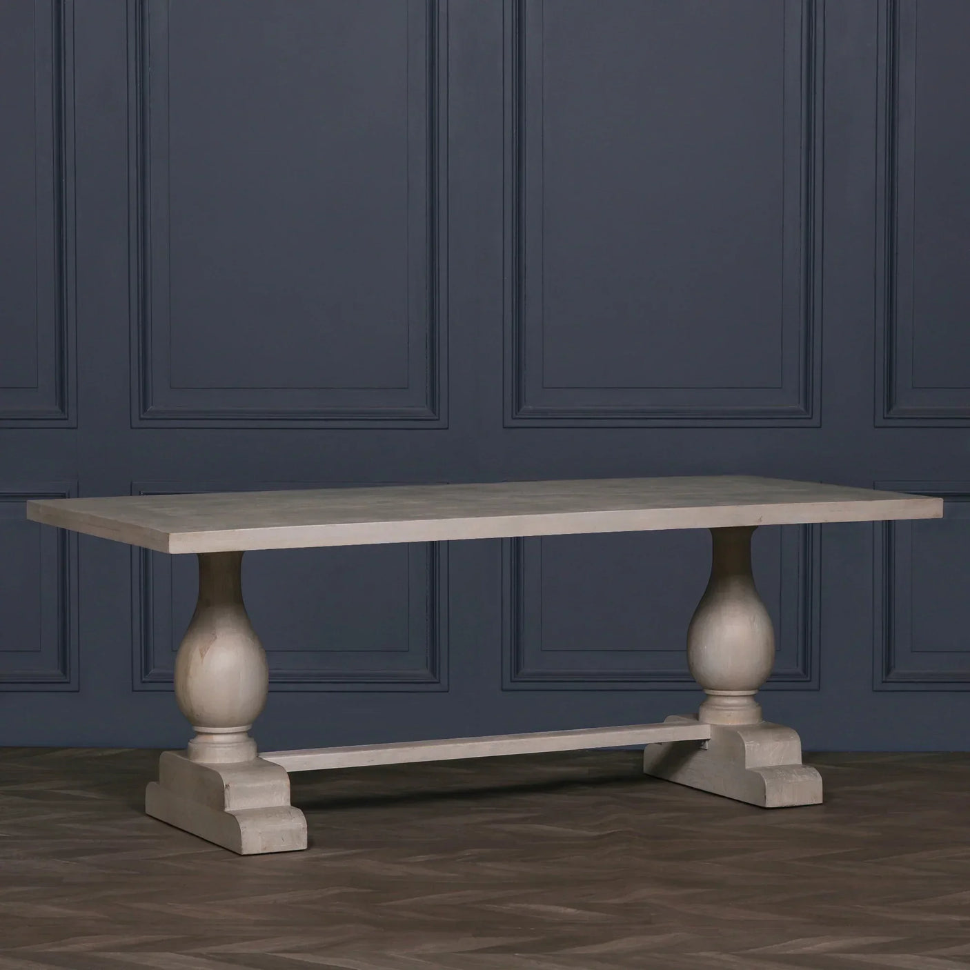 Rectangular wooden dining table with turned pedestal legs against dark blue paneled wall
