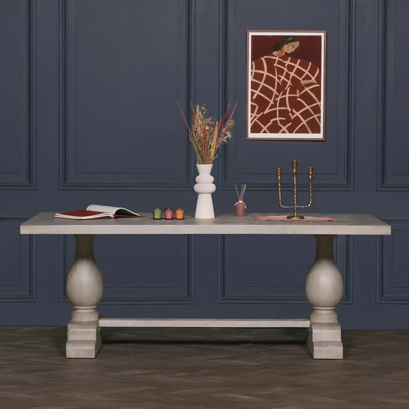 Grey wooden dining table with vase, candles, and decor against navy wall paneling