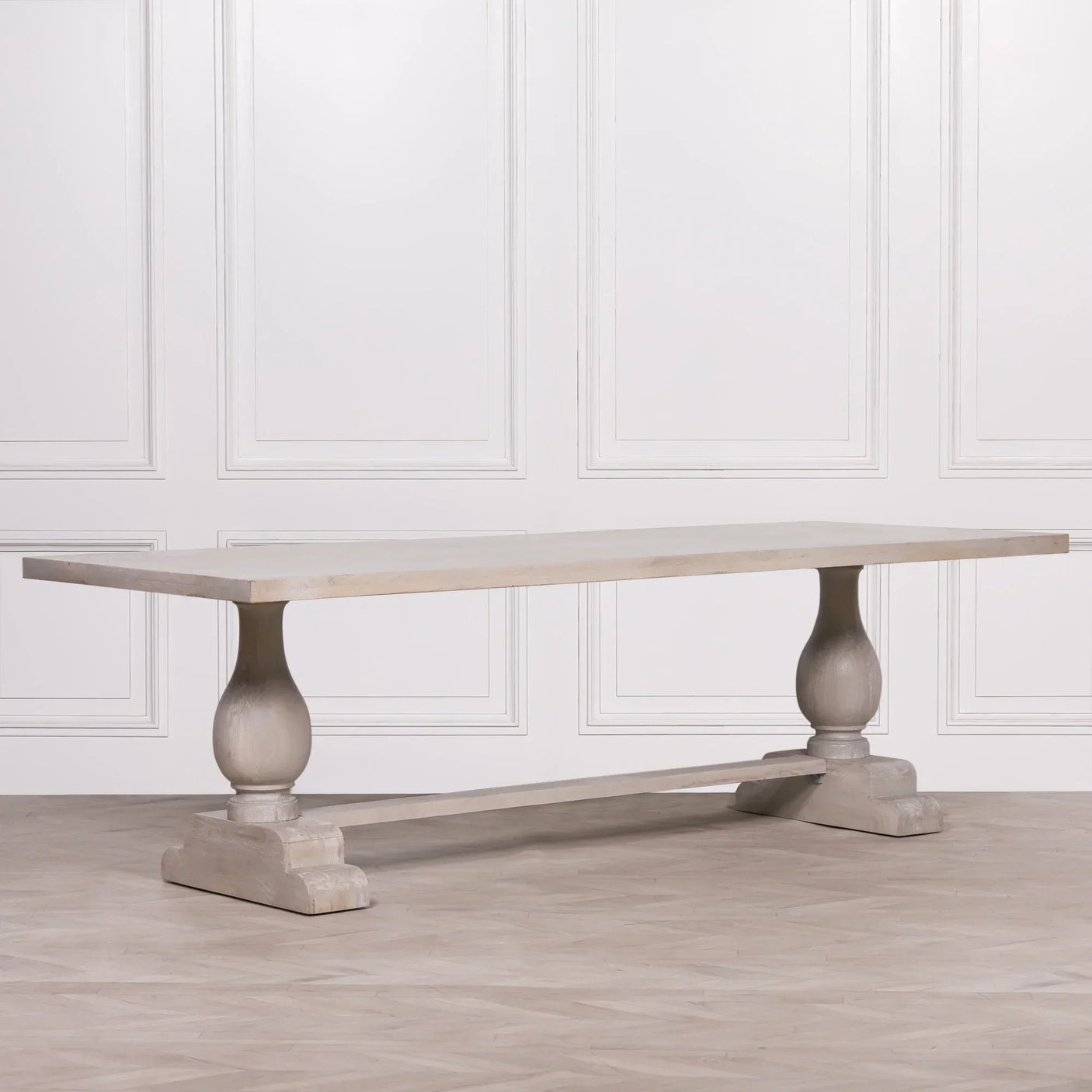 Rectangular wooden dining table with curved pedestal legs and light finish against white wall