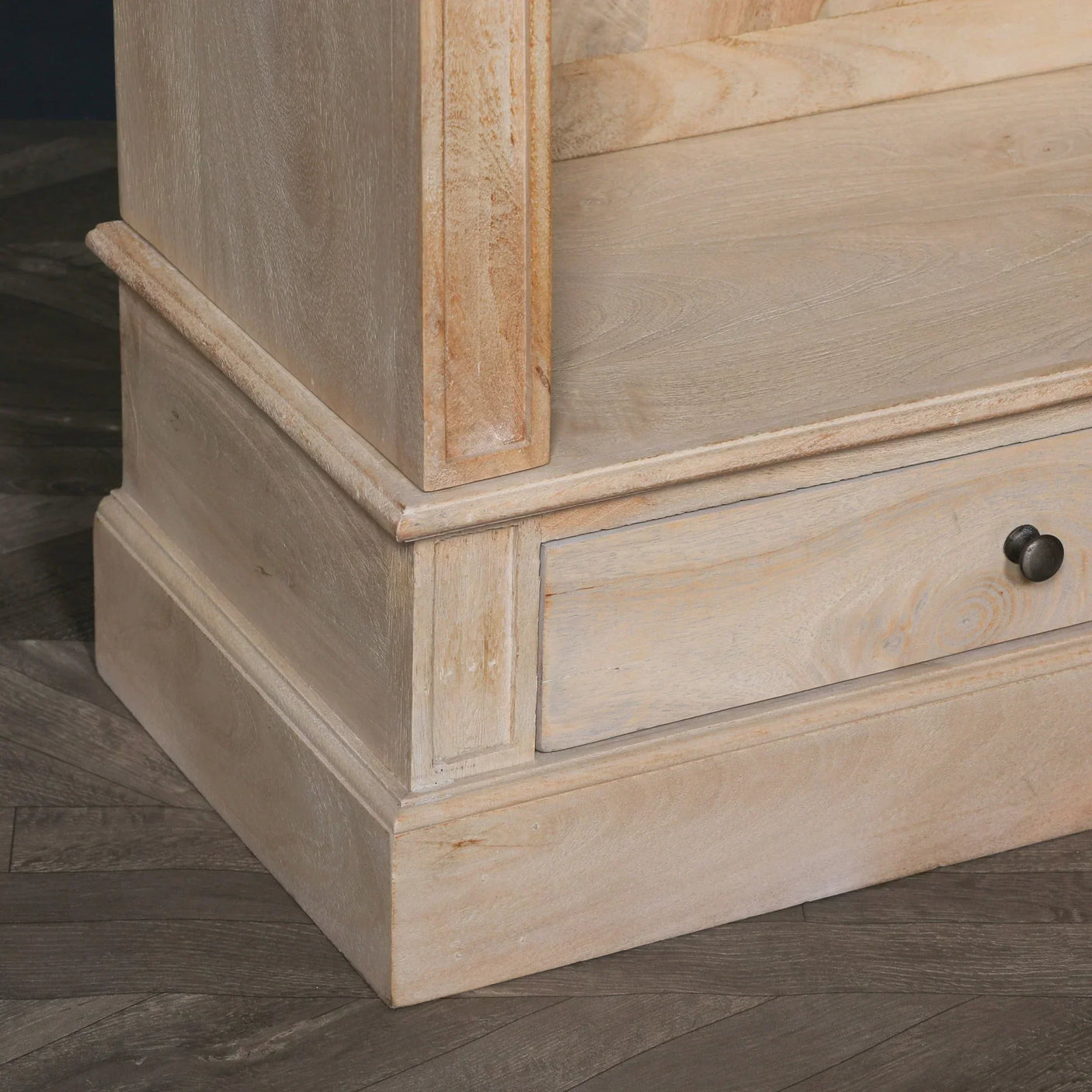 Light wood furniture base with drawer and black knob on herringbone floor