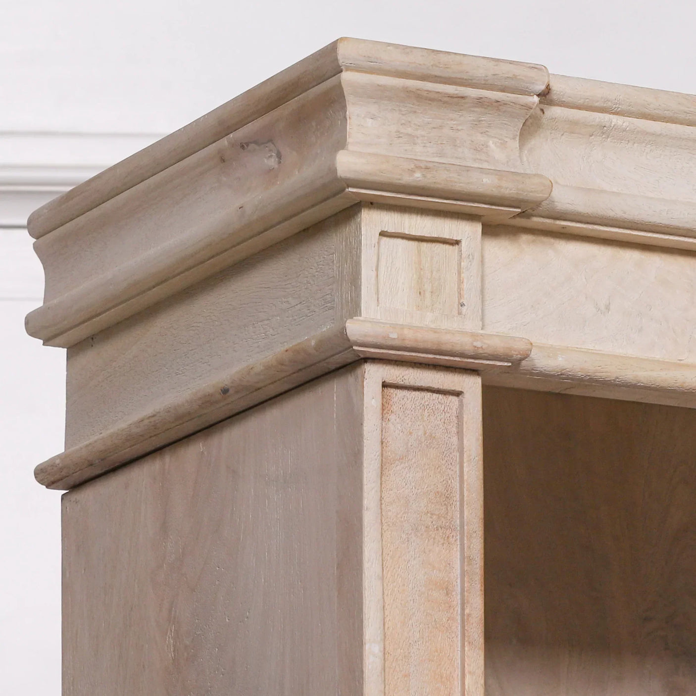 Light wood bookshelf top corner with detailed moulding and natural grain finish