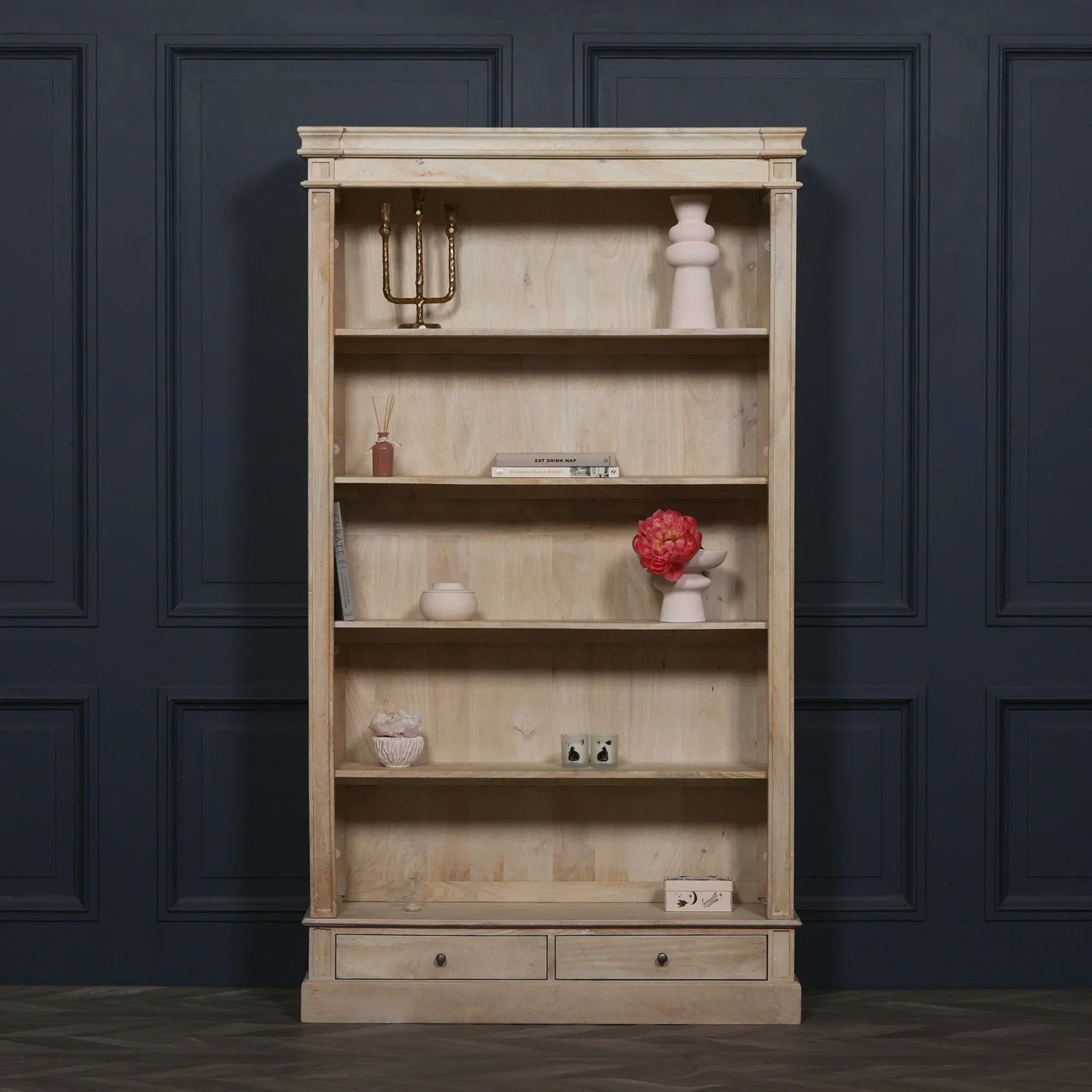 Natural wood bookcase with shelves, two drawers, and decorative home accessories