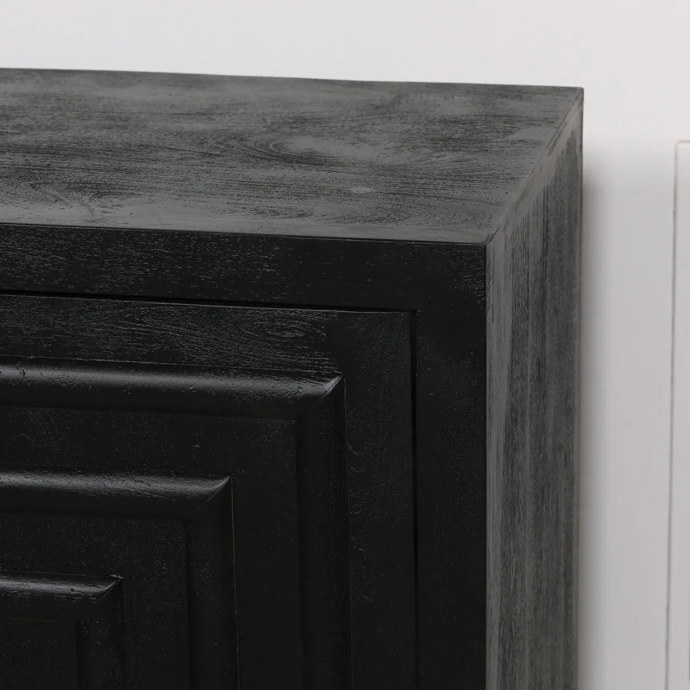 Close up of black wooden sideboard corner with textured geometric panel detailing