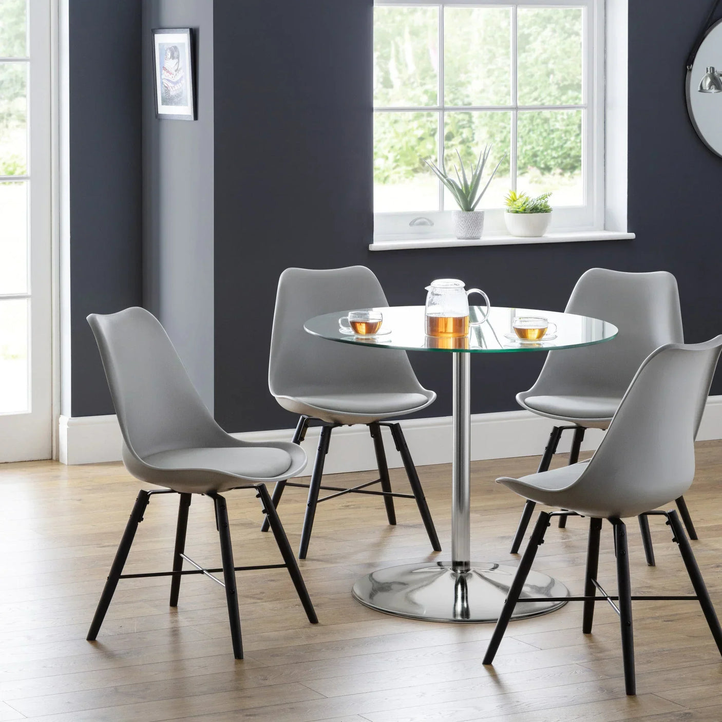 Grey dining chairs with wooden legs around round glass dining table in modern kitchen setting
