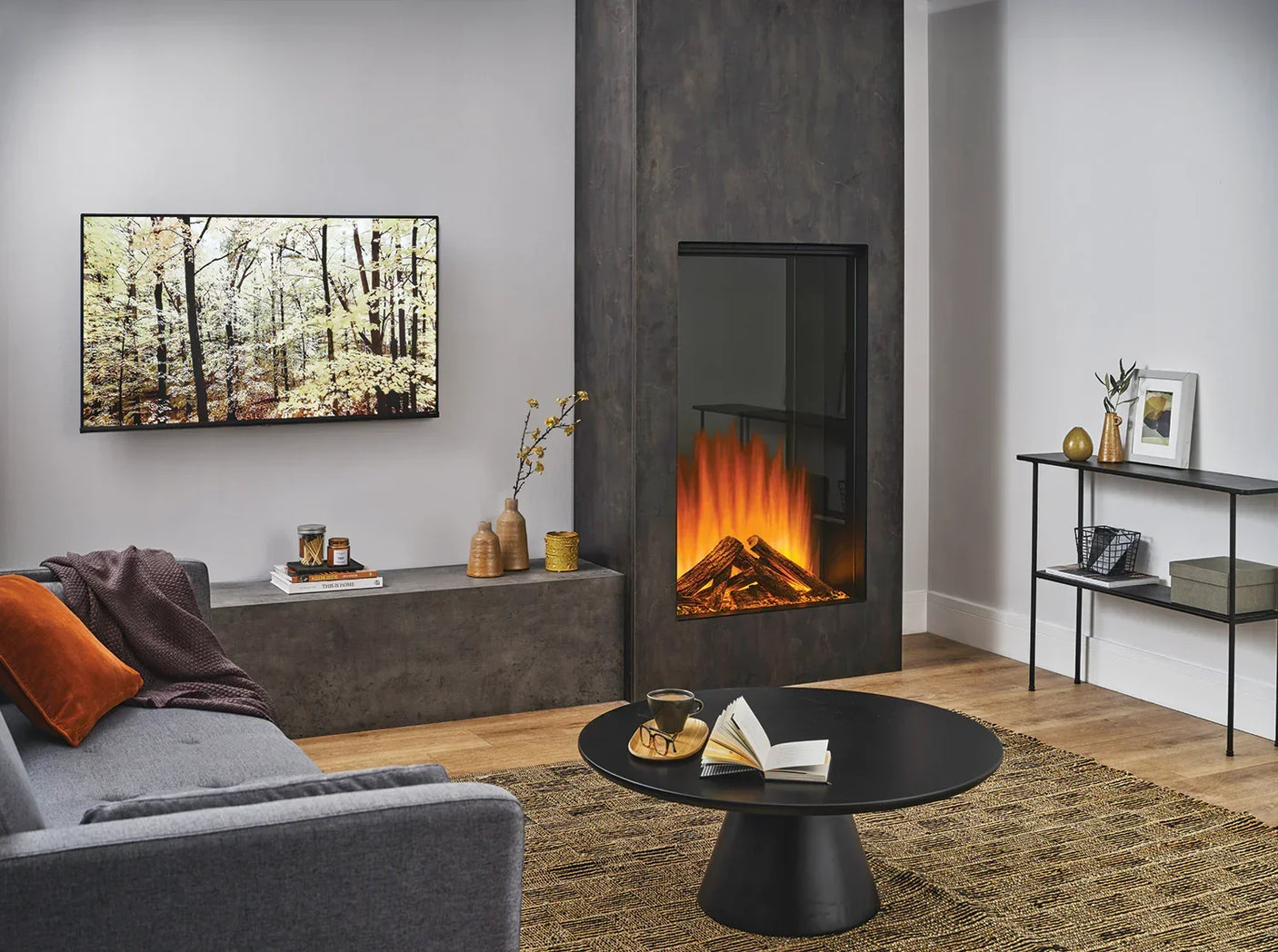 Modern living room with grey electric fireplace, round black coffee table, and grey sofa