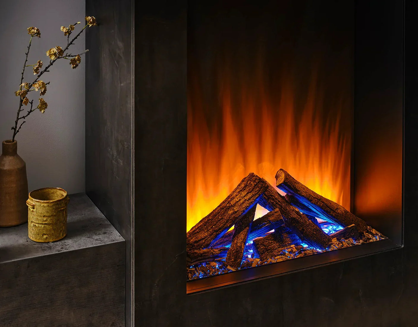 Electric fire with realistic logs and blue flames set in modern black fireplace
