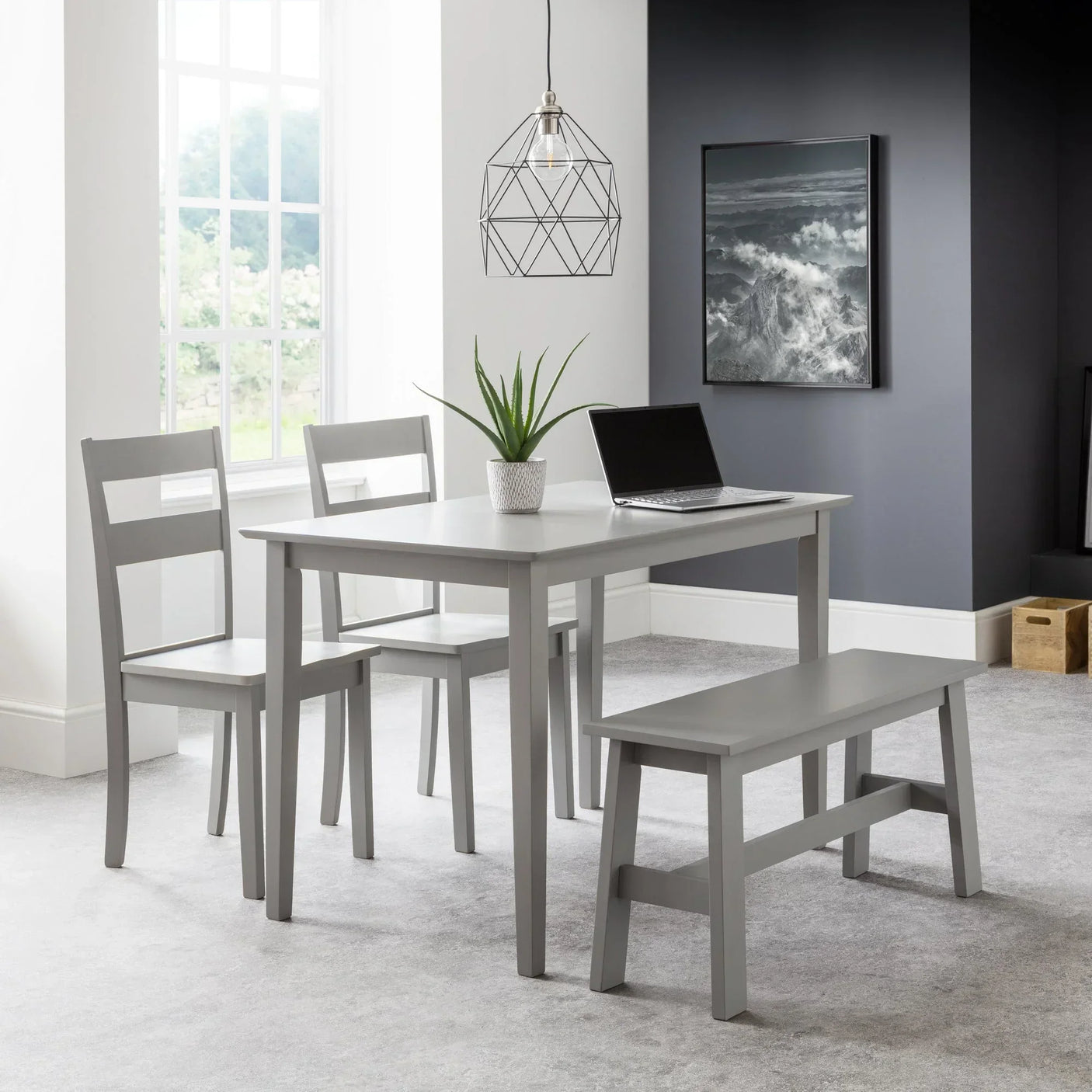 Grey dining table set with two chairs and bench in modern room with laptop and plant